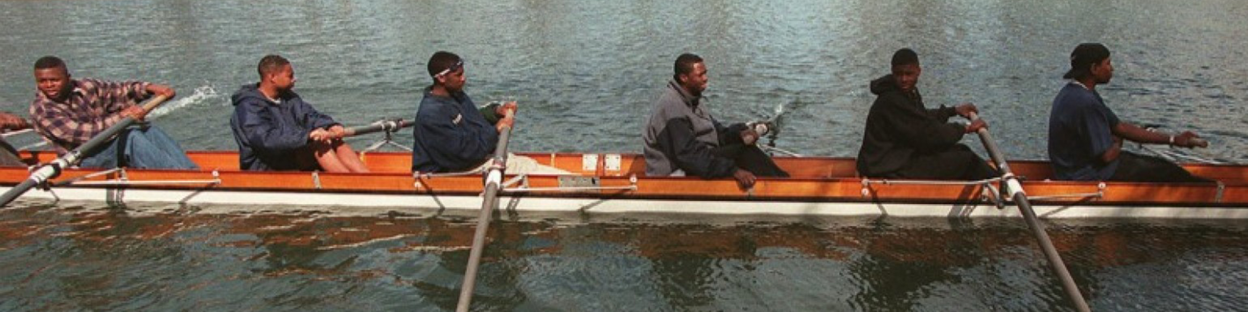 a team of young black men rowing crew