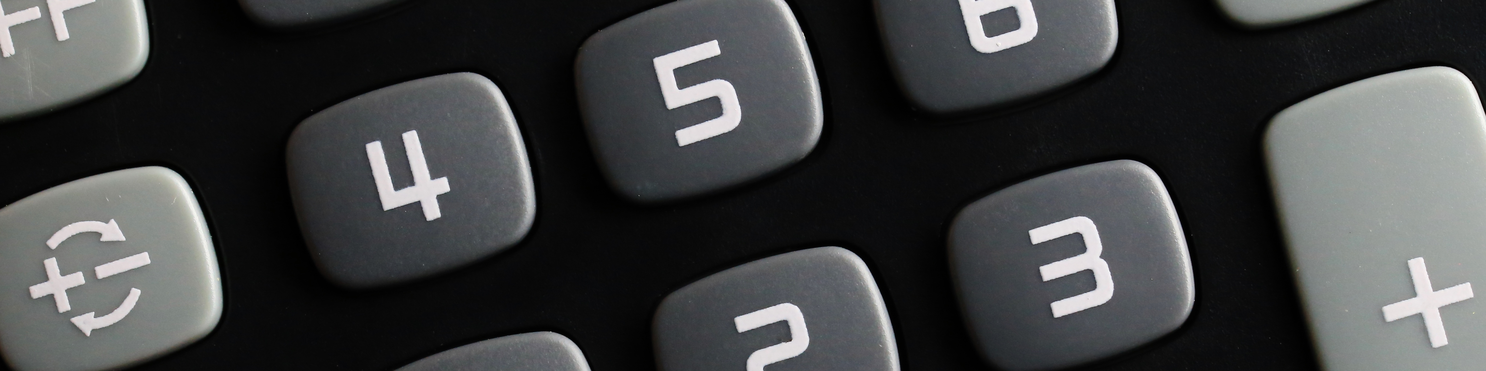 Close-up of gray and white calculator buttons on a black calculator