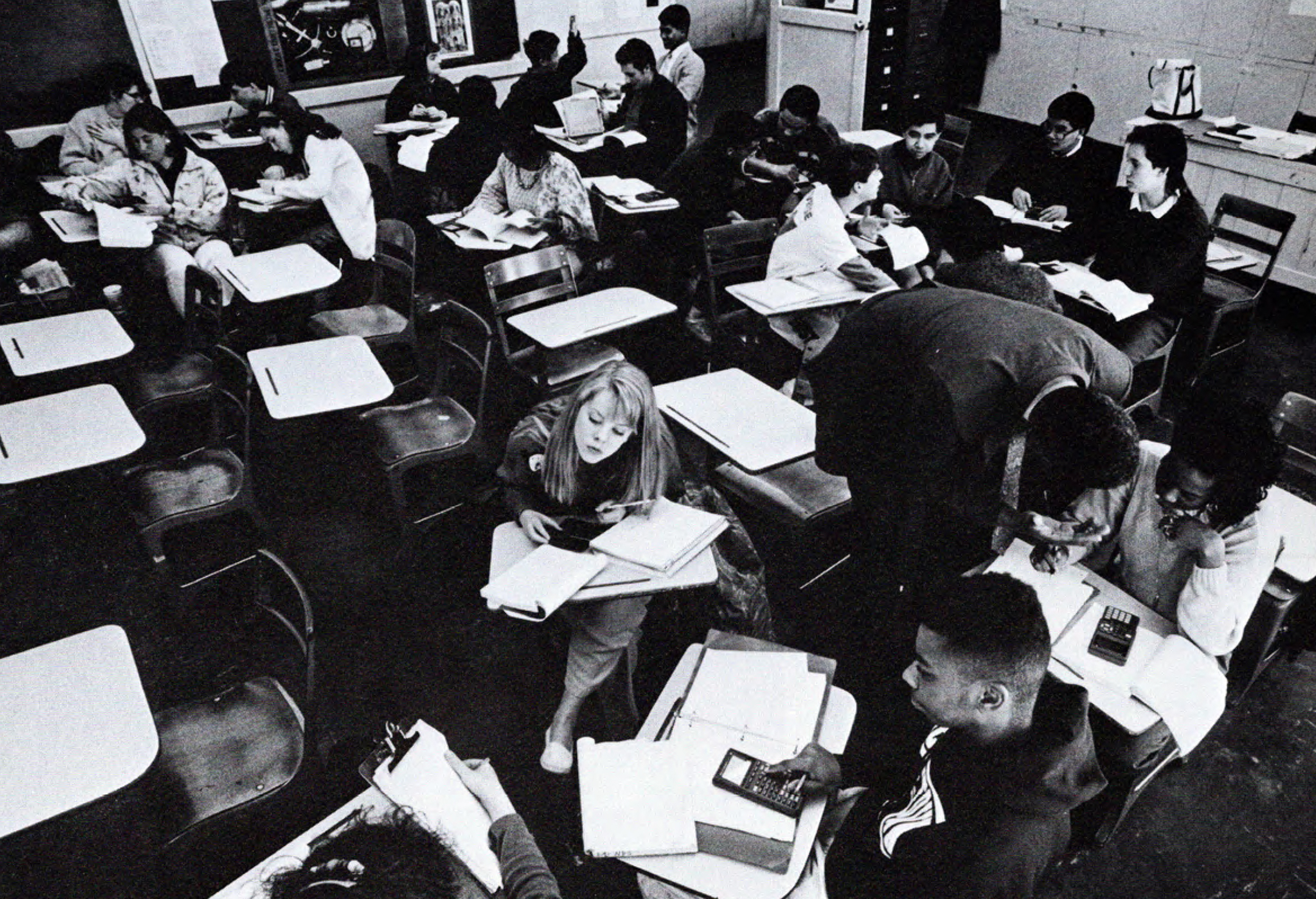 Black and white photo of a classroom where high school students do math work with calculators and notebooks while sitting at desks