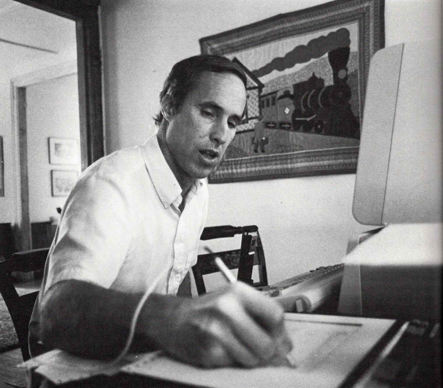 a black and white photo rom 1986 of college professor Tom Tucker sitting at a computer and writing on a tablet with a stylus connected to the computer