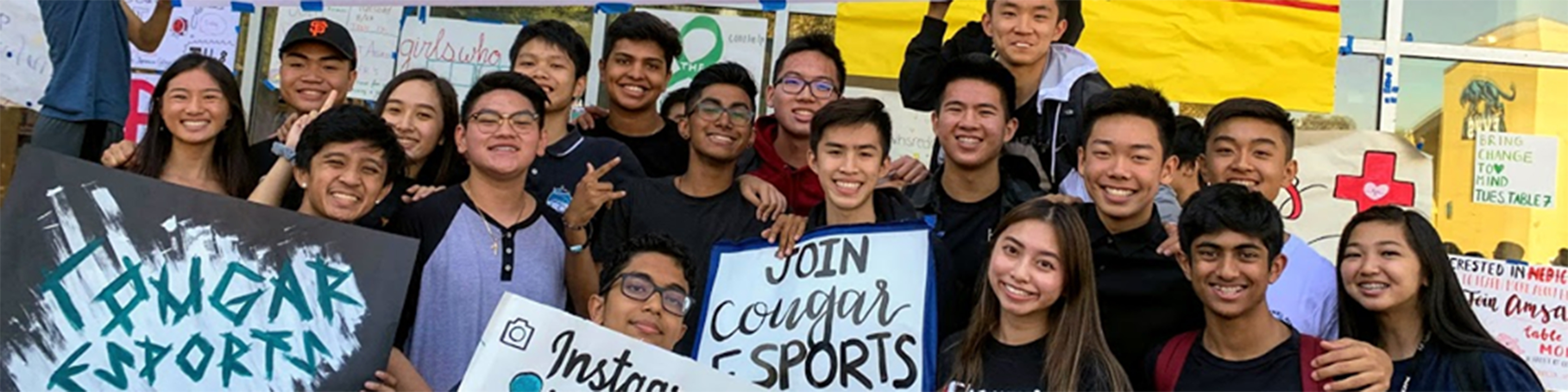 a group of teenage young men and young women from the Evergreen Valley High School e sports team holding up signs promoting e sports