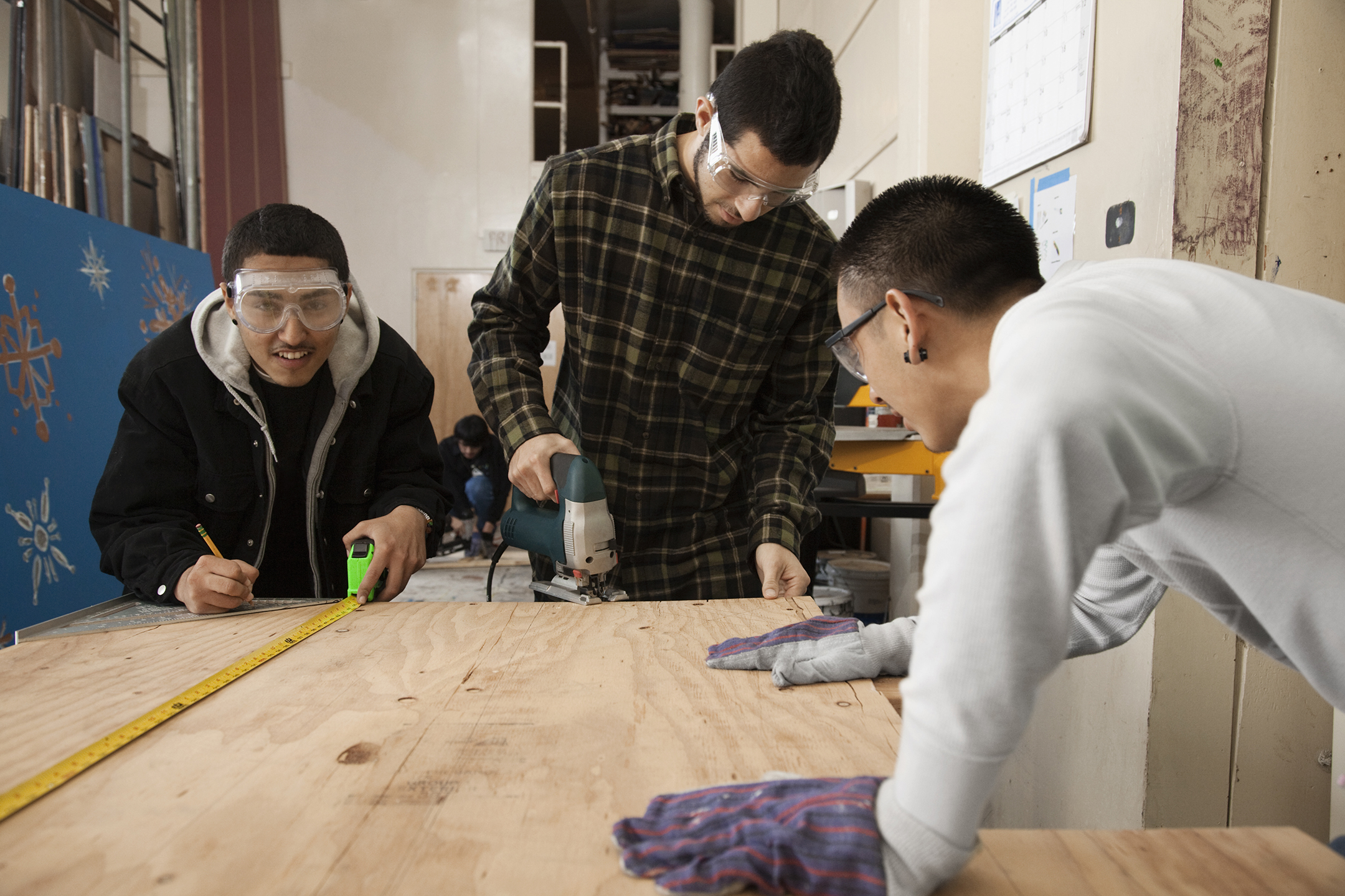 students in shop class working with a saw on a woodworking project