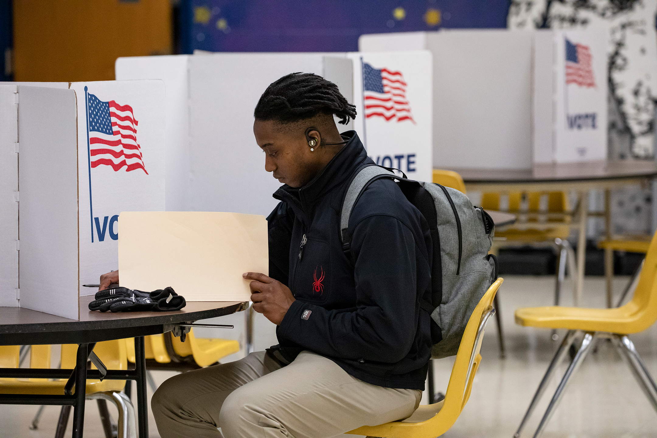 A young man sits at a voting booth during the 2020 presidential primary election