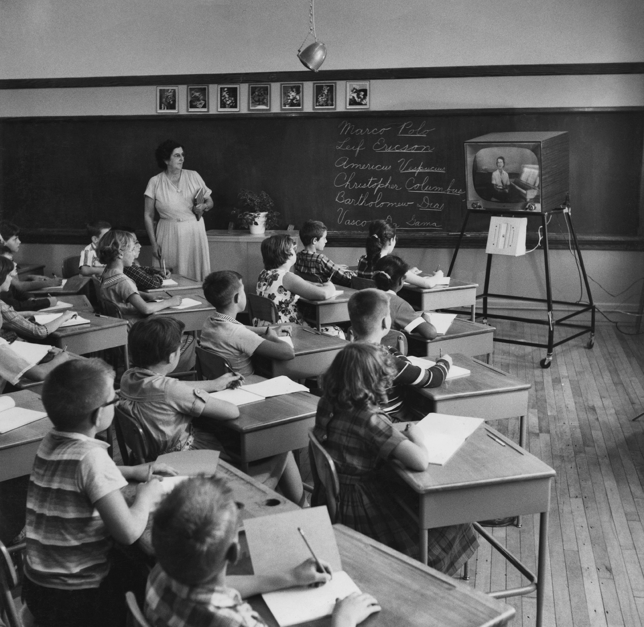 black and white photo of a classroom of students watching a lesson on a television
