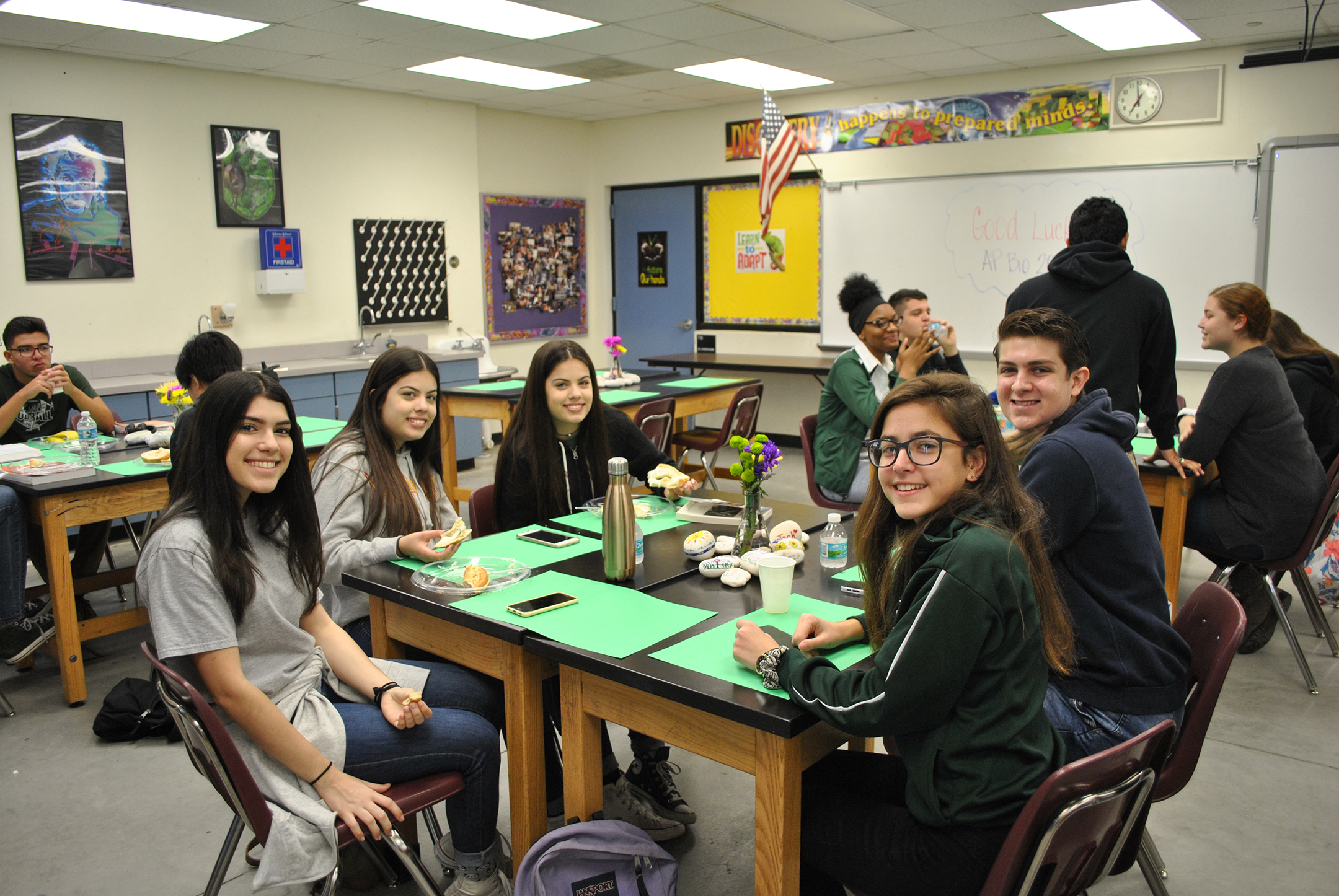 students sit around a table in a classroom eating breakfast