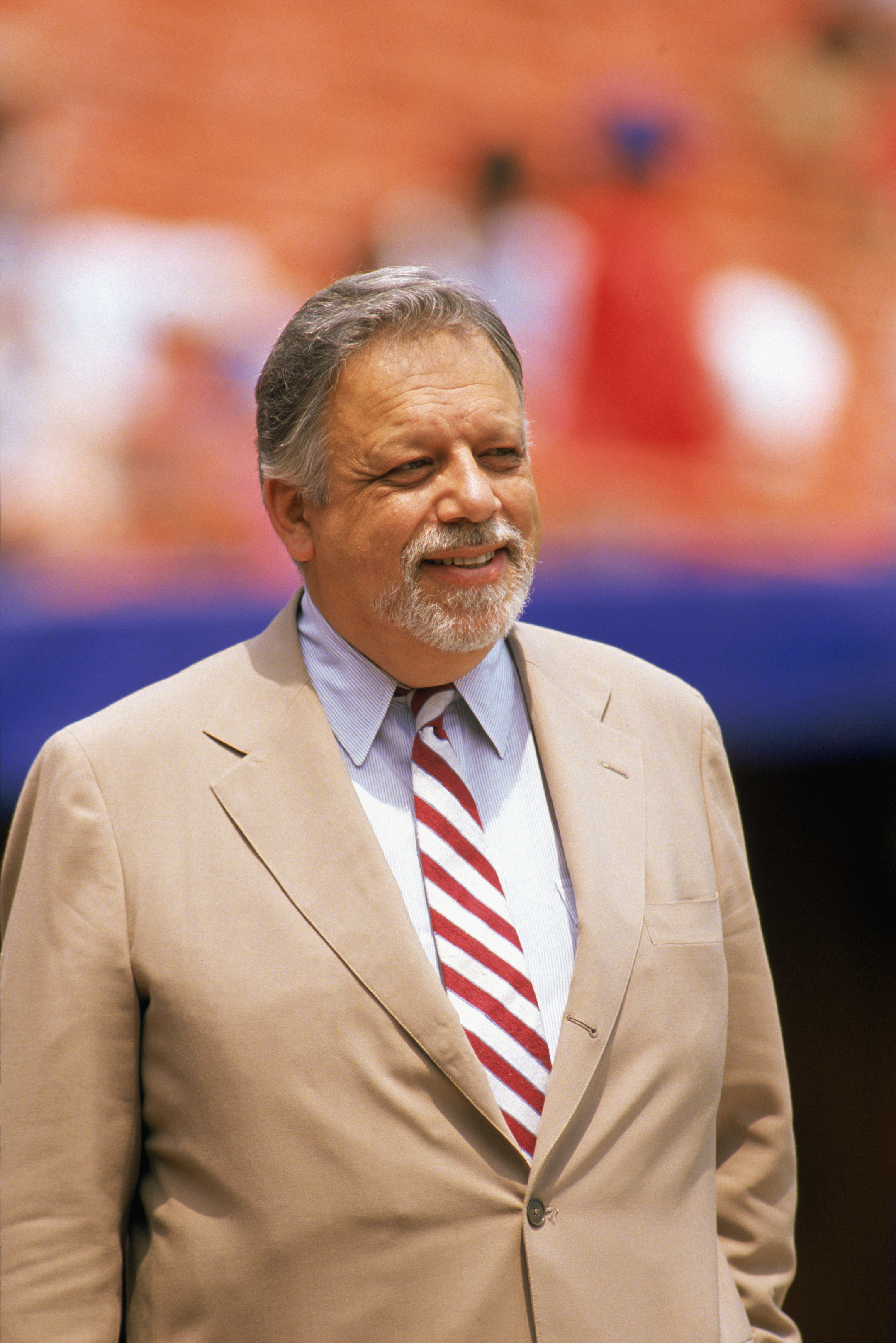 Baseball commissioner A. Bartlett Giamatti standing on a baseball field in a light suit and striped tie