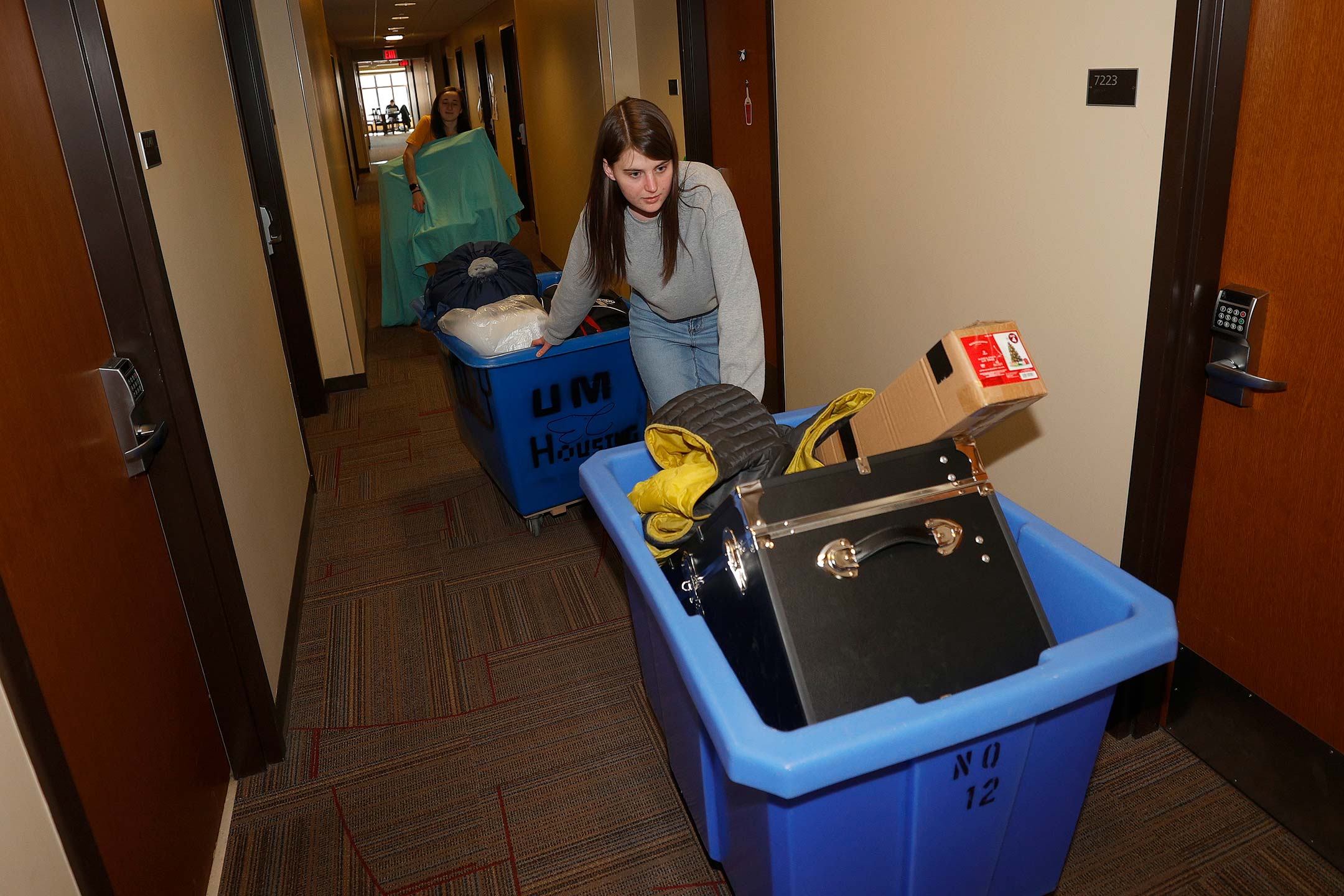 A female college student pushes a cart full of her belongings as she moves out of her dorm