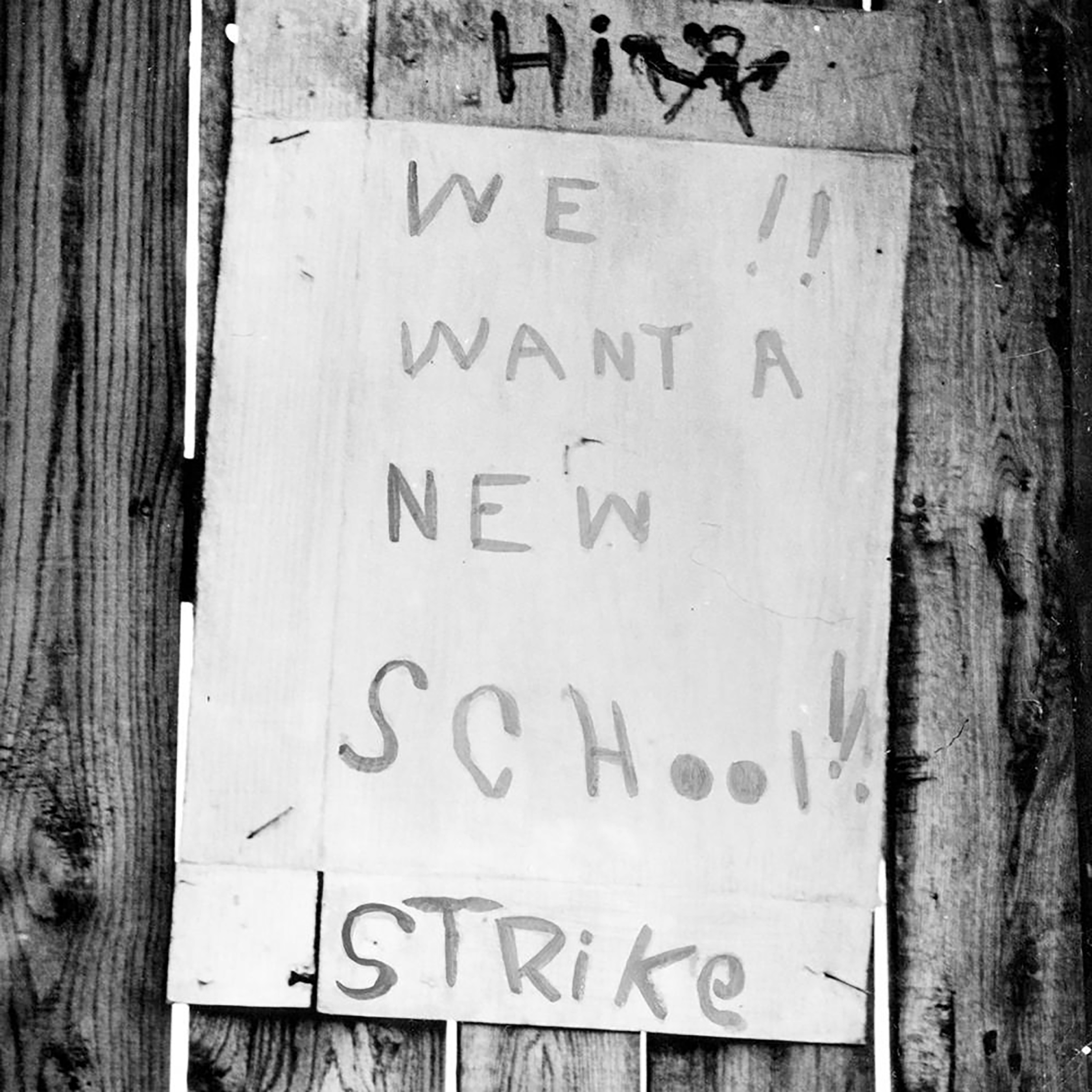 emade sign created by students in 1951 protesting wretched conditions at their school. the sign reads "hi we want a new school! strike"