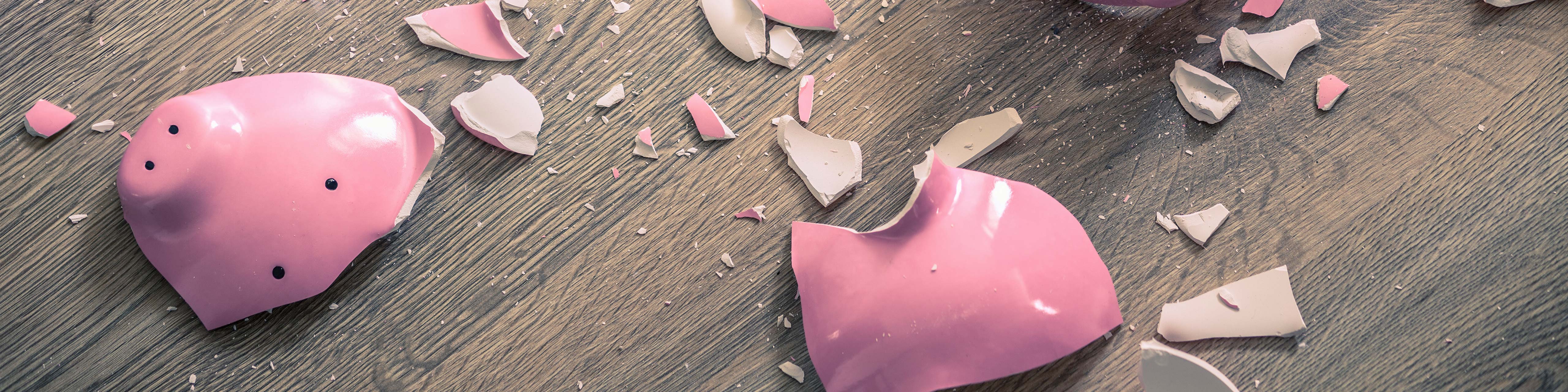 a pink piggy bank lays smashed on the floor