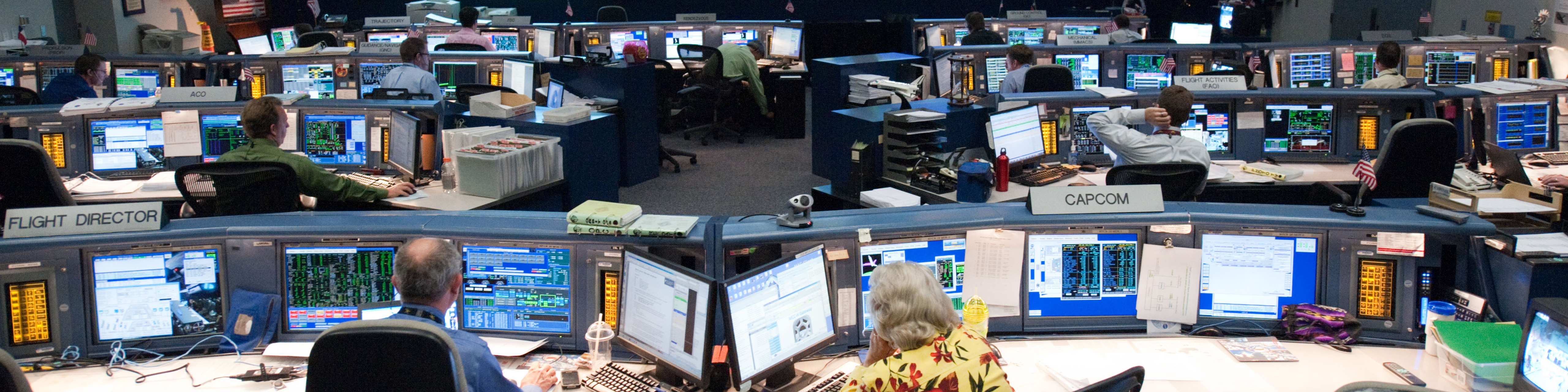 wide angle shot of nasa's mission control center, showing people sitting at computer terminals