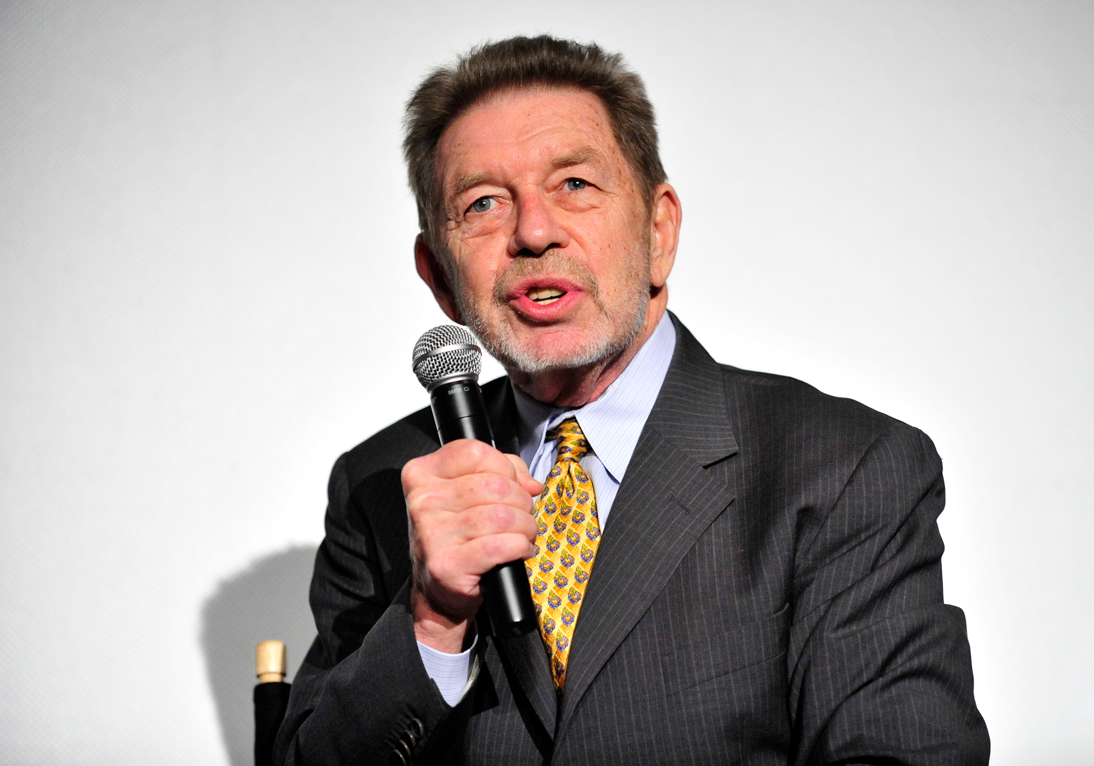 pete hamill holds a microphone as he speaks at a movie premiere
