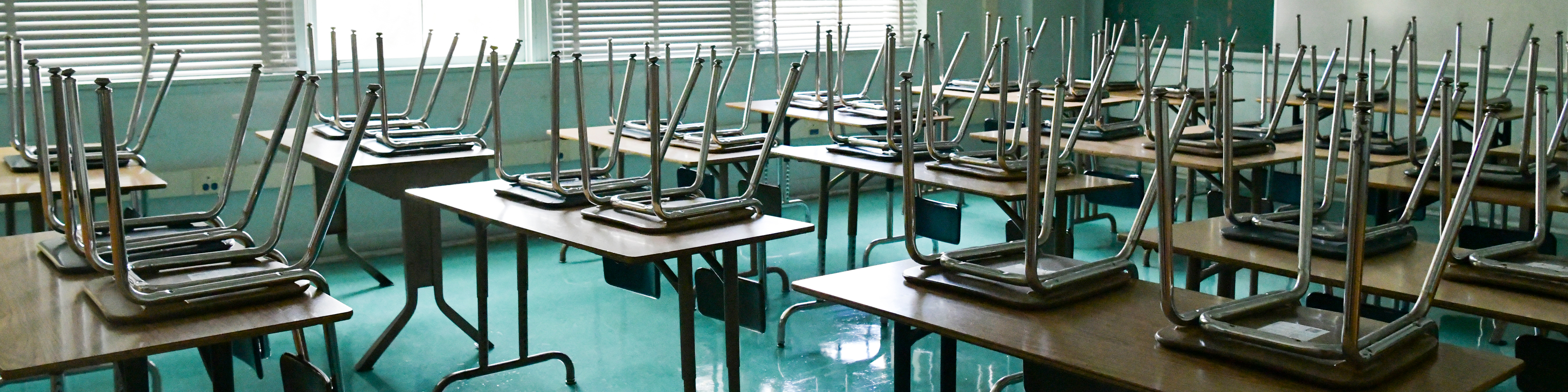 an empty classroom with chairs on top of desks