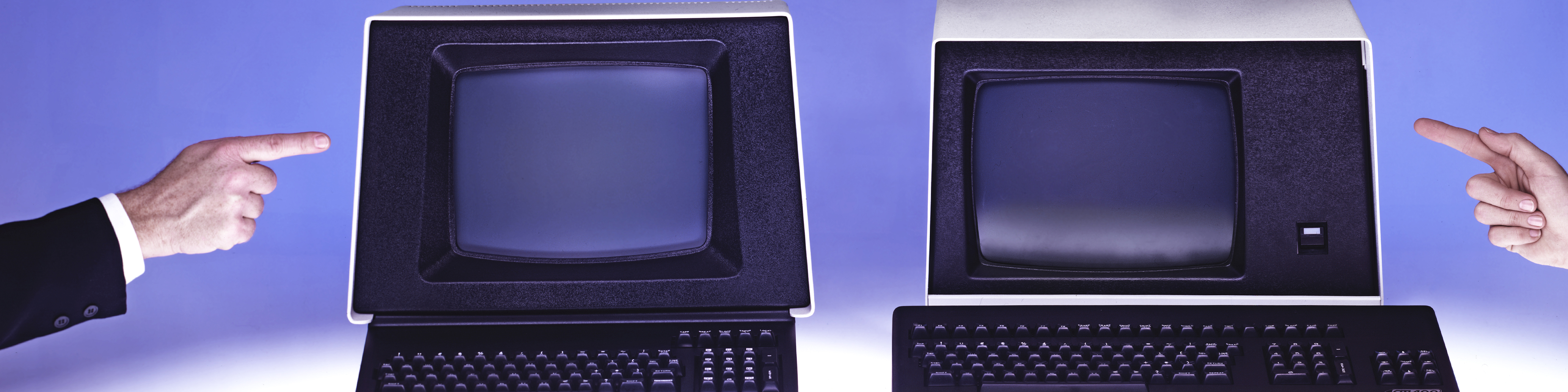 two hands pointing at two old computer terminals set against a blue-purple background