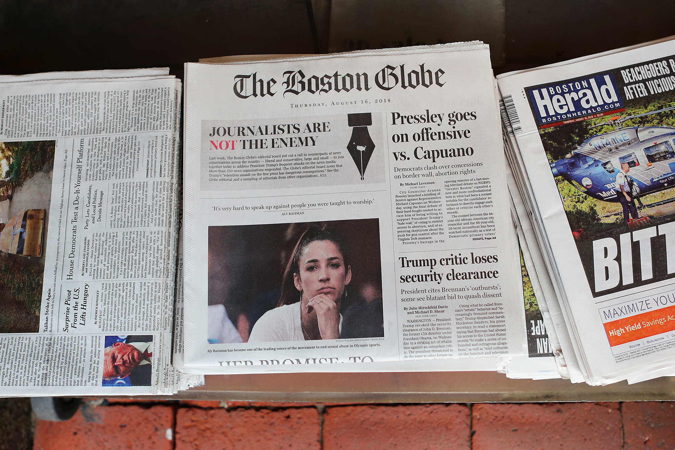 A row of newspapers with the boston globe in the middle with the headline journalists are not the enemy