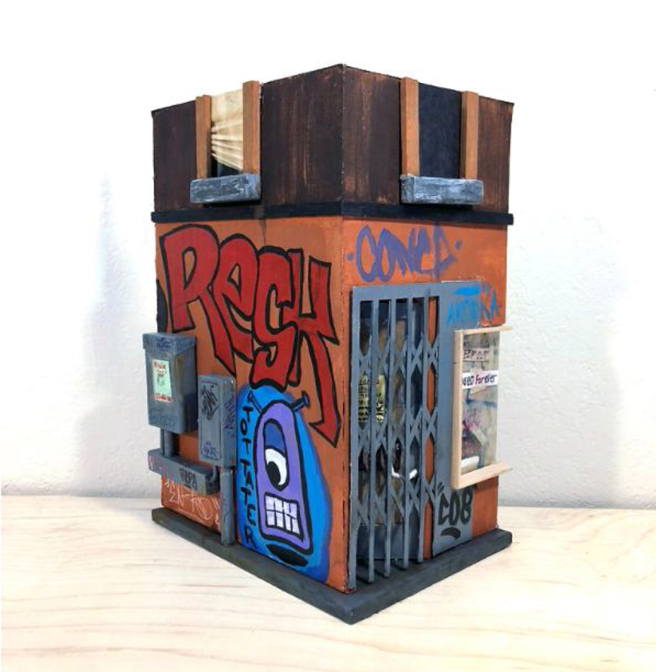 A miniature reproduction of a corner bodega with its security gate on and graffiti all over the building