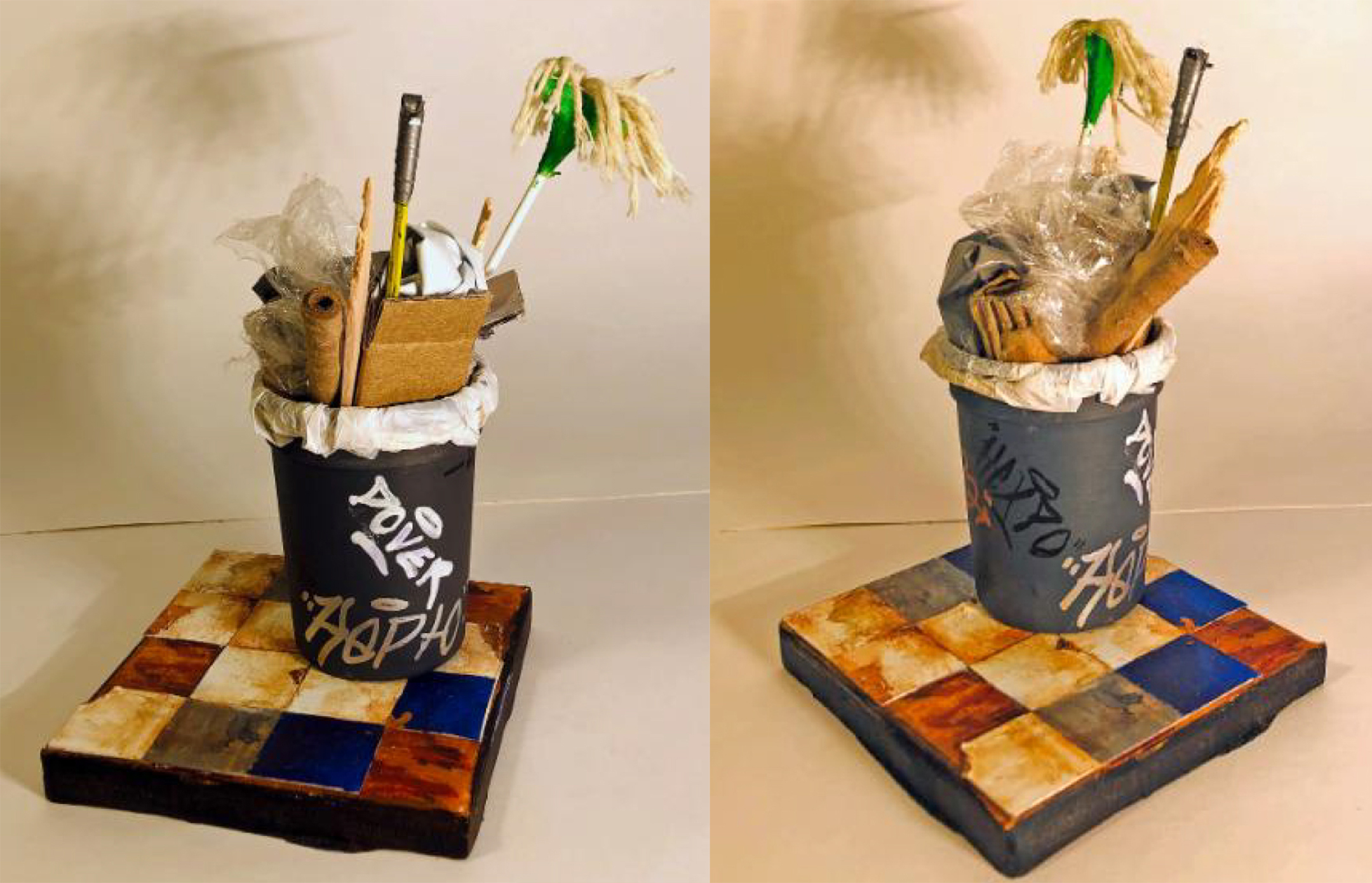 A miniature reproduction of a plastic trash can with mops and brooms sticking out of it 