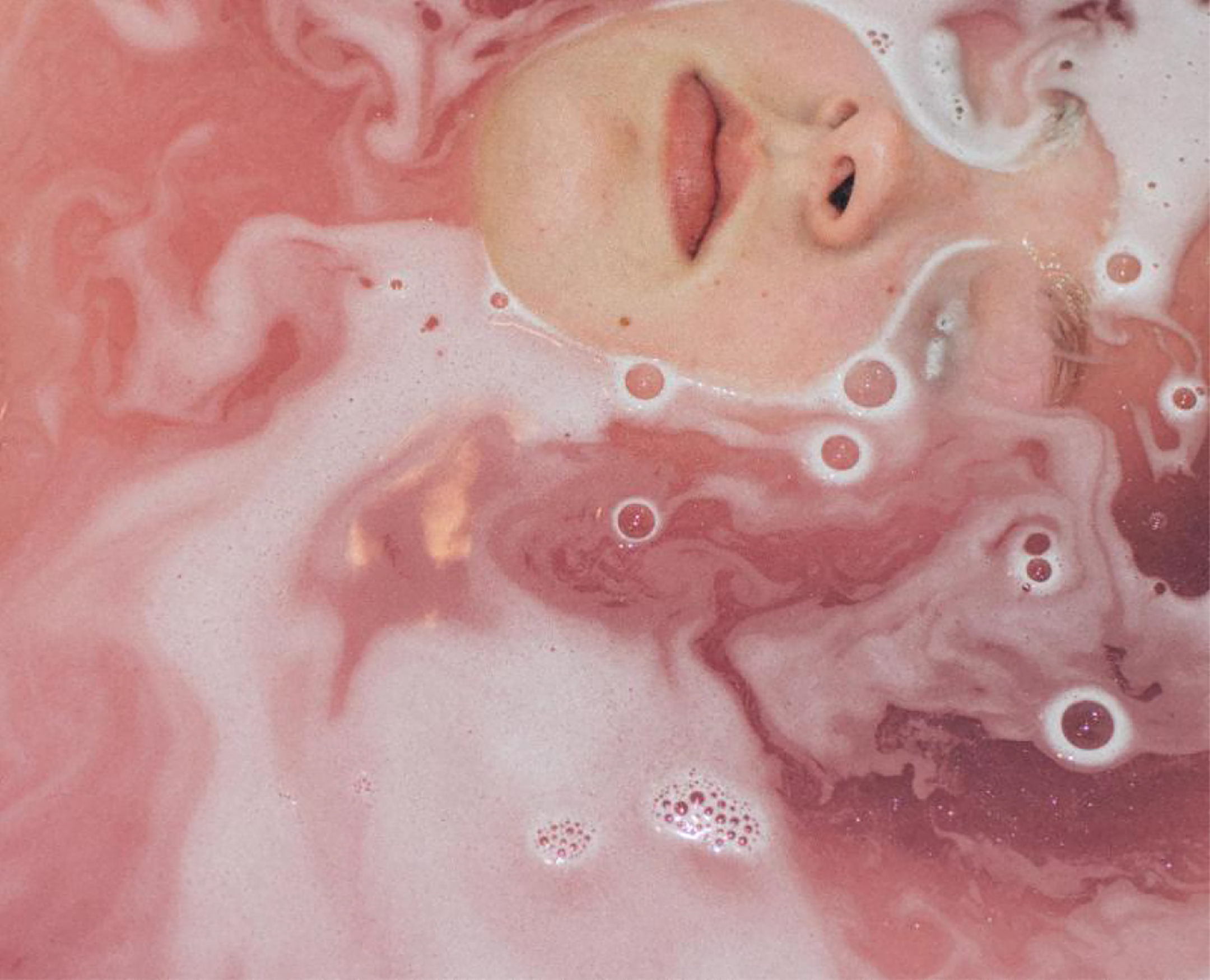 An abstract photo self-portrait of a young woman's face peeking out from below pink water