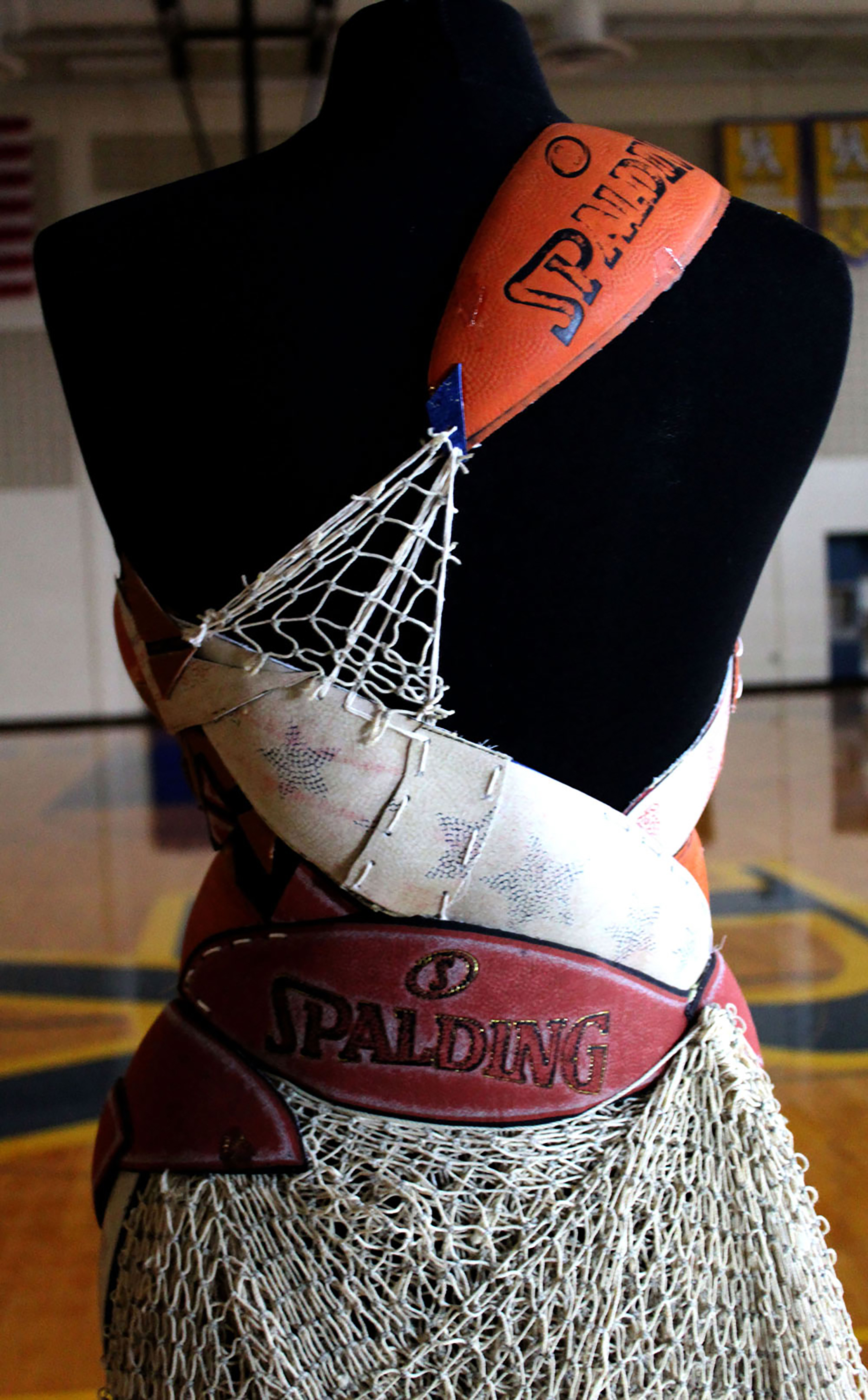 Detail of a dress made out of old basketballs and netting, showing the upper body of the dress with a shoulder strap made out of a basketball