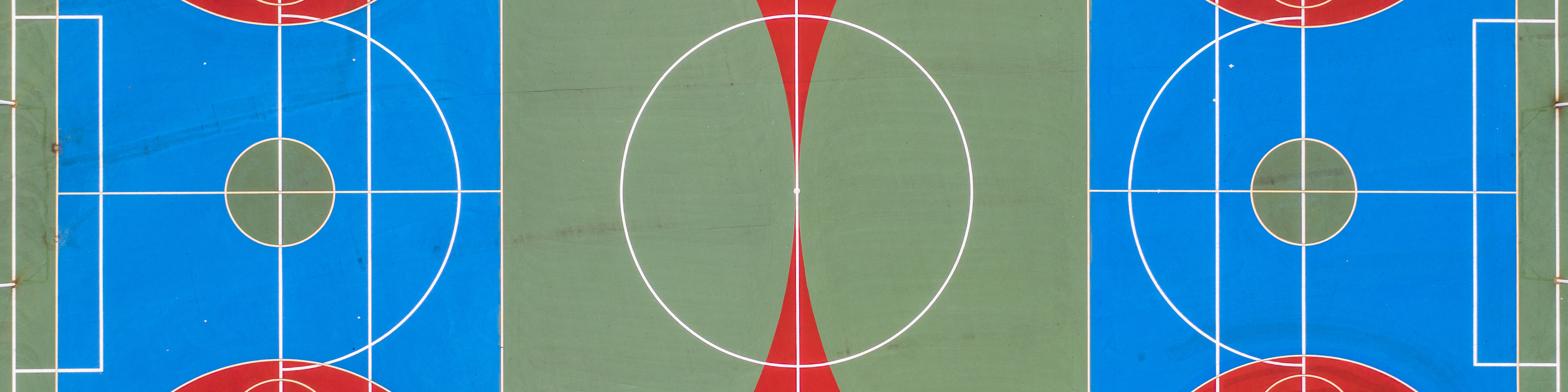 An overhead view of a hard-surface soccer field in red, green, and blue