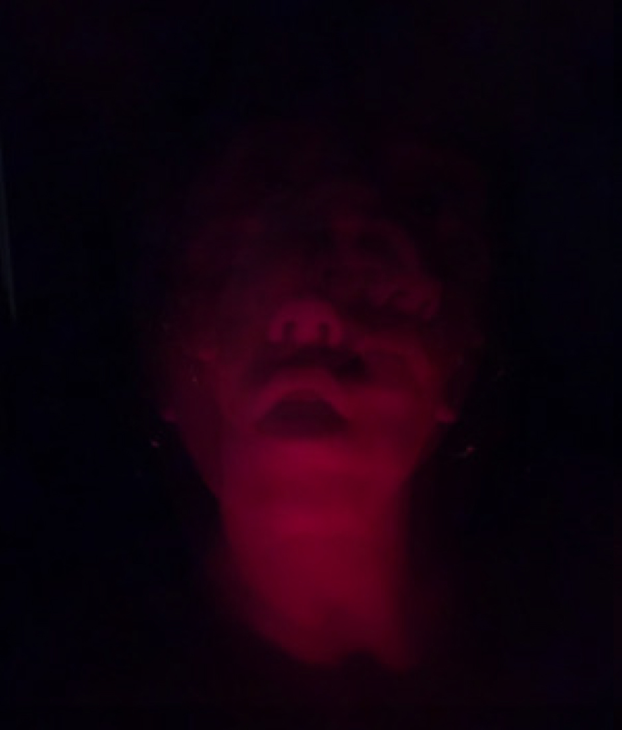 Photo of a person in red light and shadow so they're only seen from the nose down