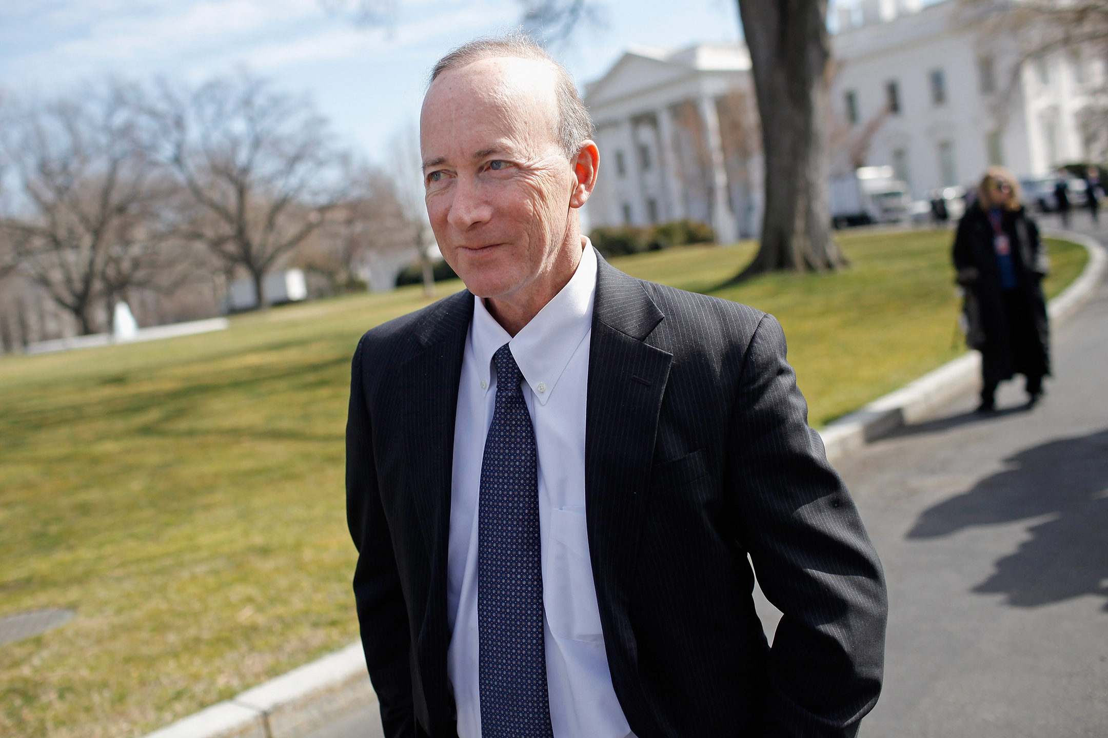 Mitch Daniels in a suit walking away from the White House