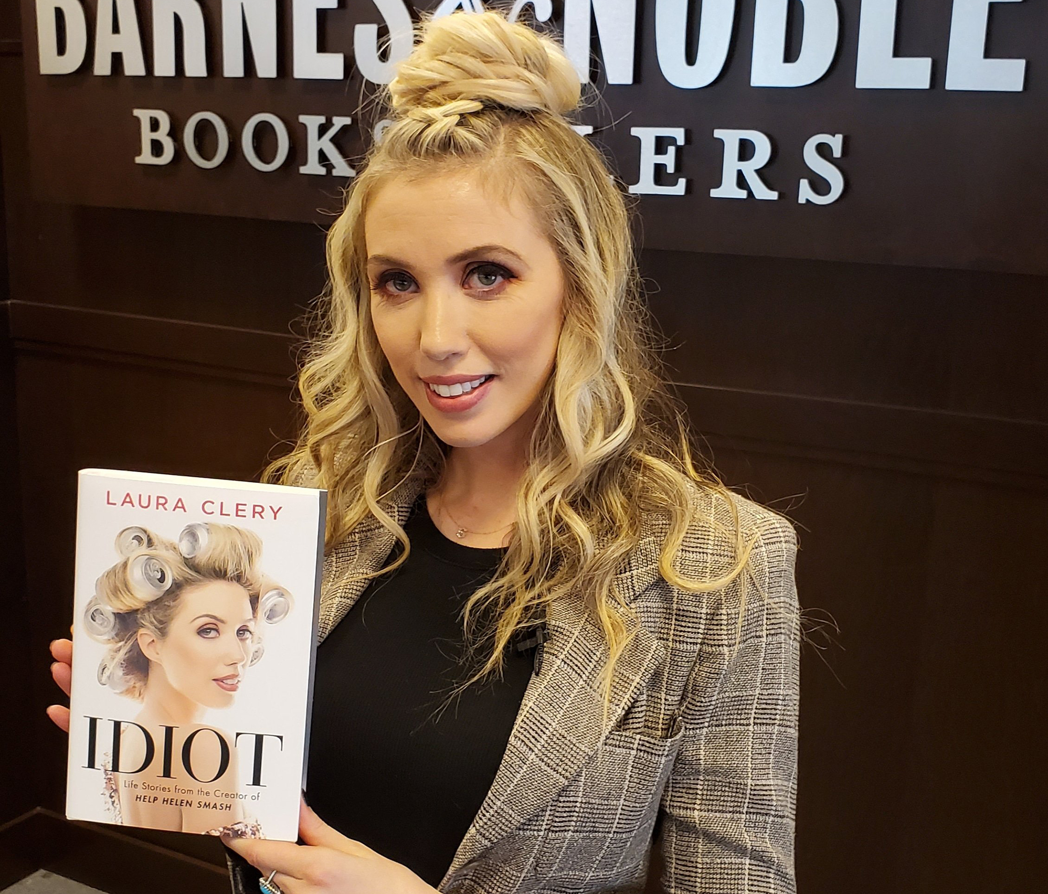 Photo of author Laura Clery holding her book idiot