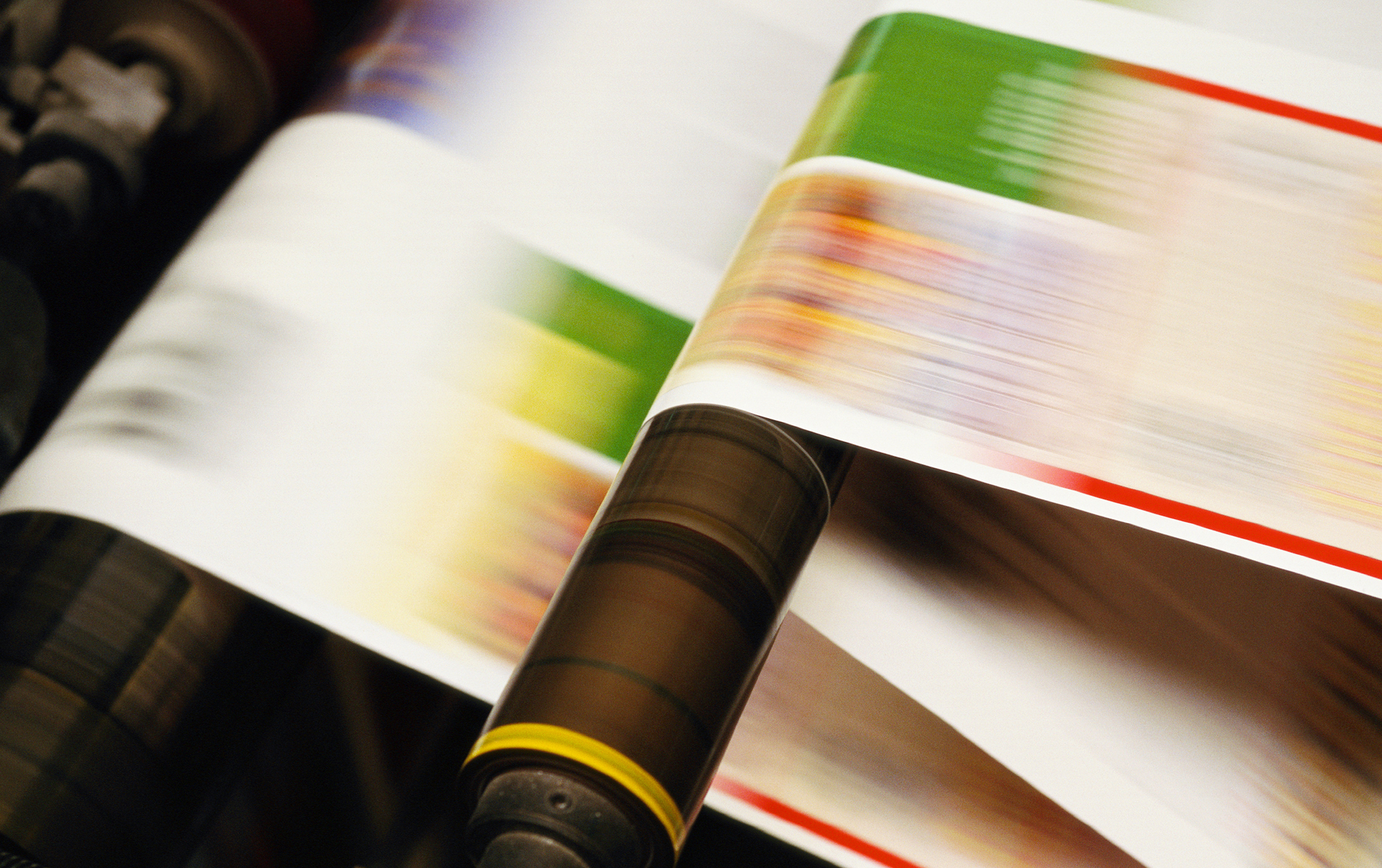 Close up photograph of pages of a magazine moving at high speeds through a printing press