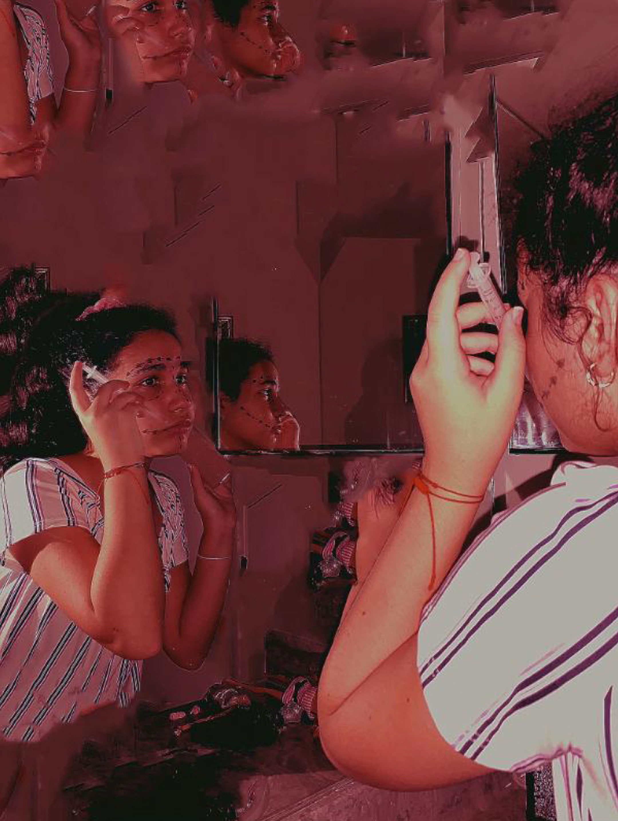 Photograph of a young woman looking in the mirror and manipulating her face