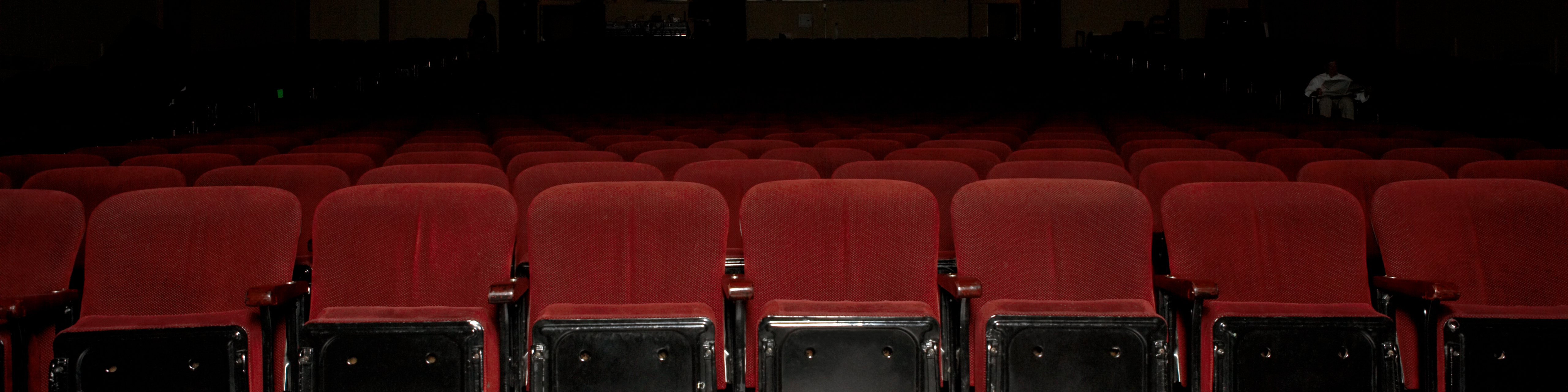 Row of empty movie theater seats with popcorn strewn on the floor