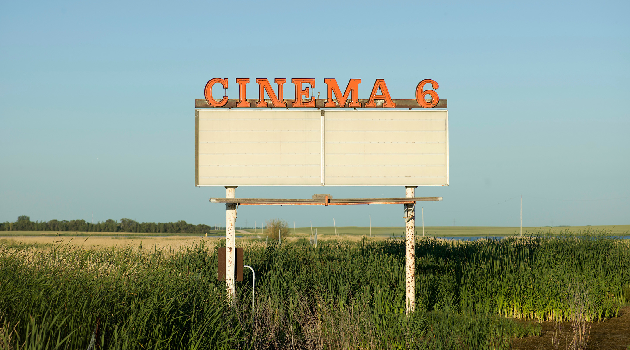 An empty movie theater marquee sign with Cinema 6 above it standing in an empty field