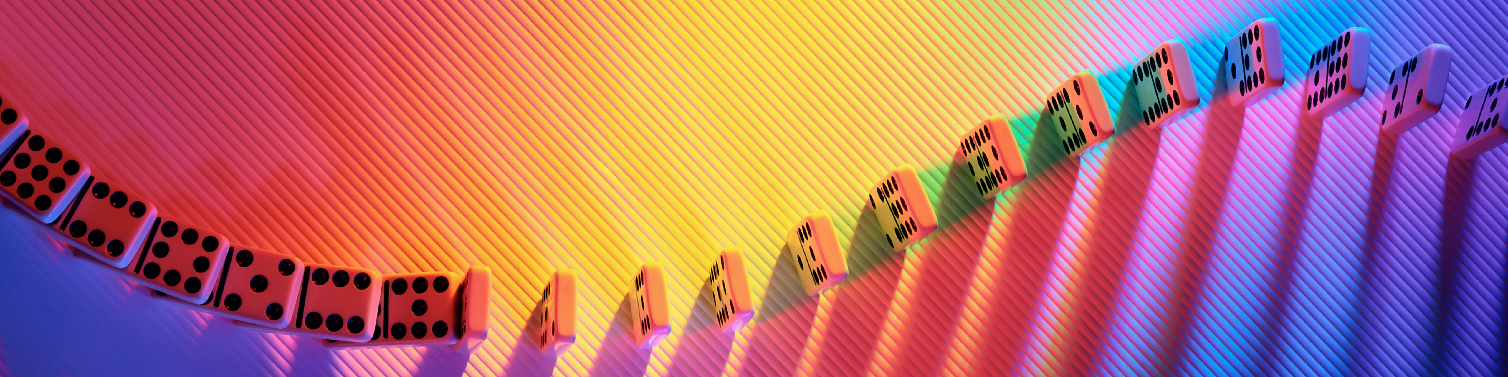 Row of dominos twisting and turning on a rainbow-colored floor