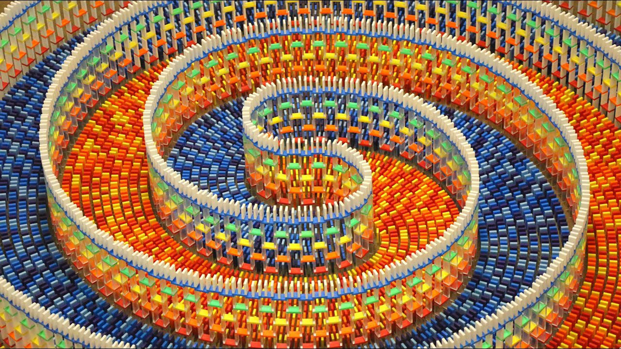 Thousands of dominos organized in a multi-colored spiral