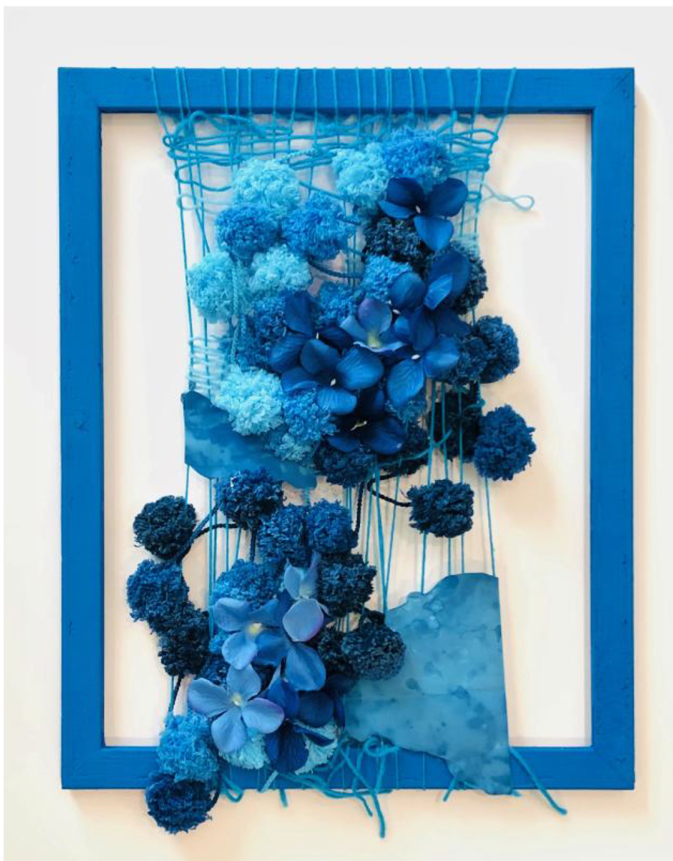 An empty blue picture frame with an arrangement of blue threads and flower-like items hung in it