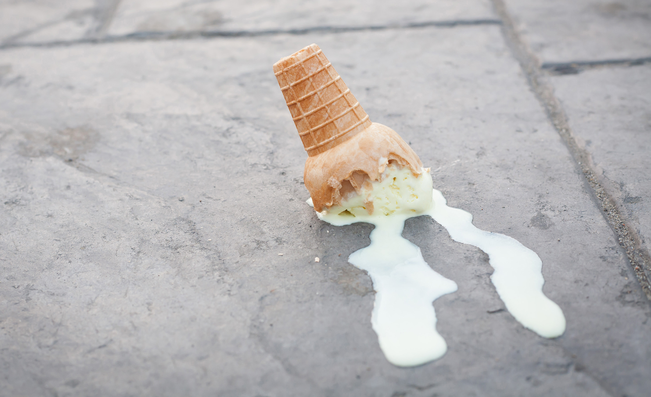 Upside down ice cream cone melting down a sidewalk