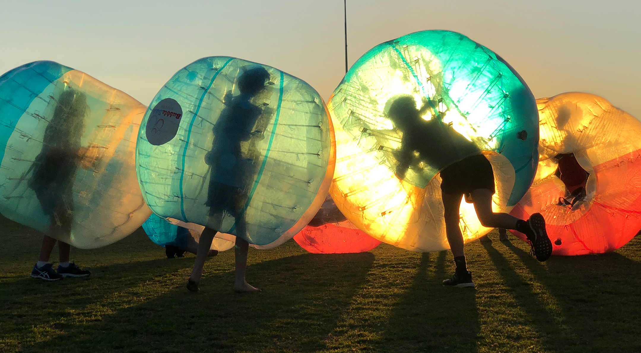 Kids playing bubble soccer as the sun sets