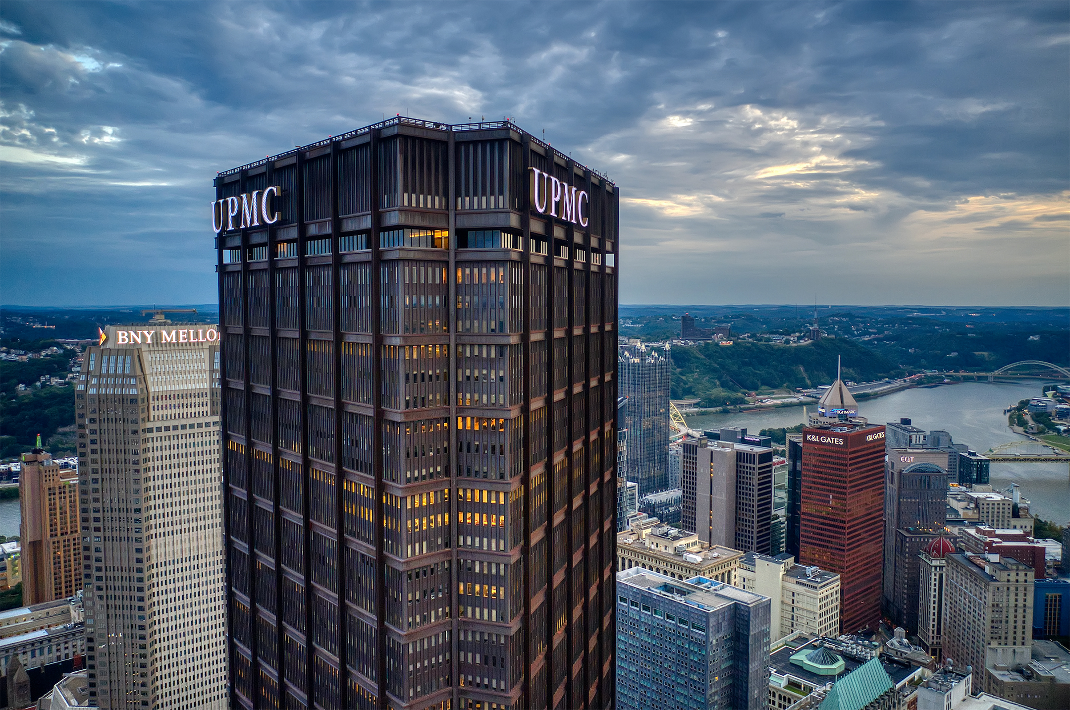 View of the US Steel Building in Pittsburgh with white UPMC letters hung on the top of the black skyscraper, seen from the air with the building looming over others