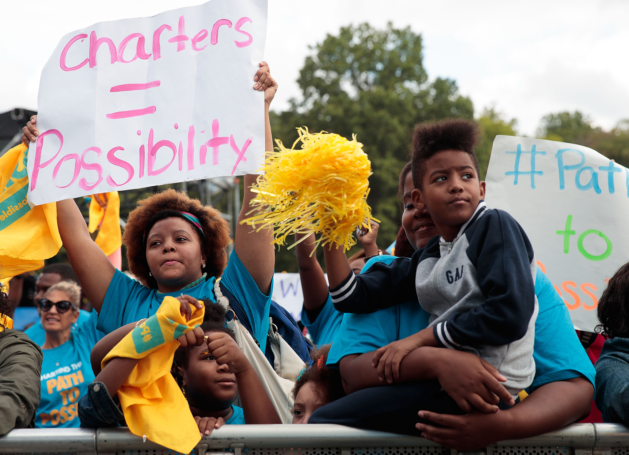 Family protesting school inequality by holding up signs that read charters = possibility