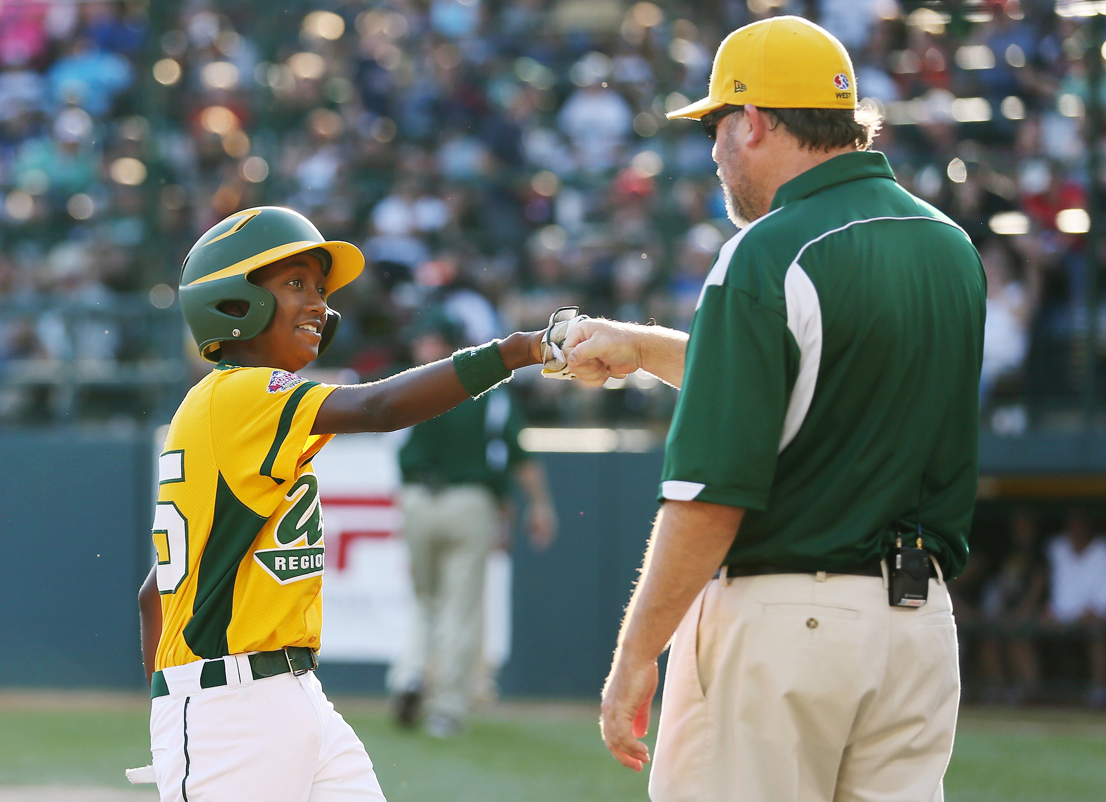 Young black baseball player fist bumps his older male white coach