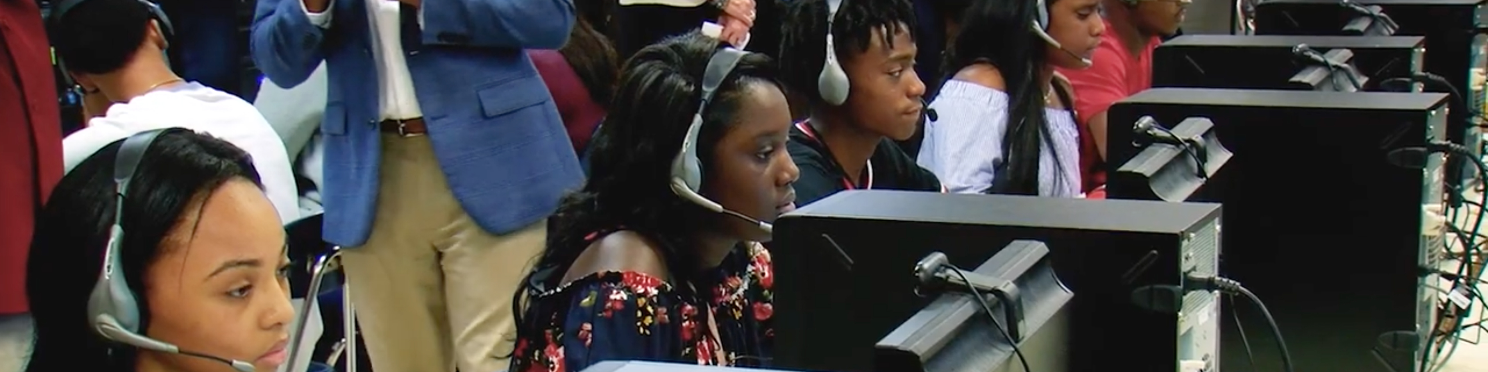 Class of black students sitting at computers, wearing headsets