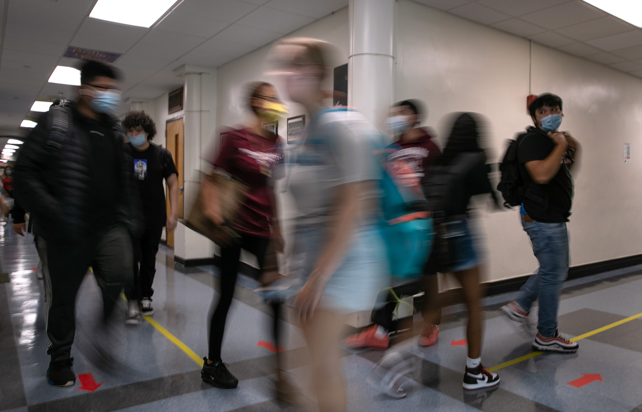 Blurry, in-motion photo of students walking through a school's hallways.