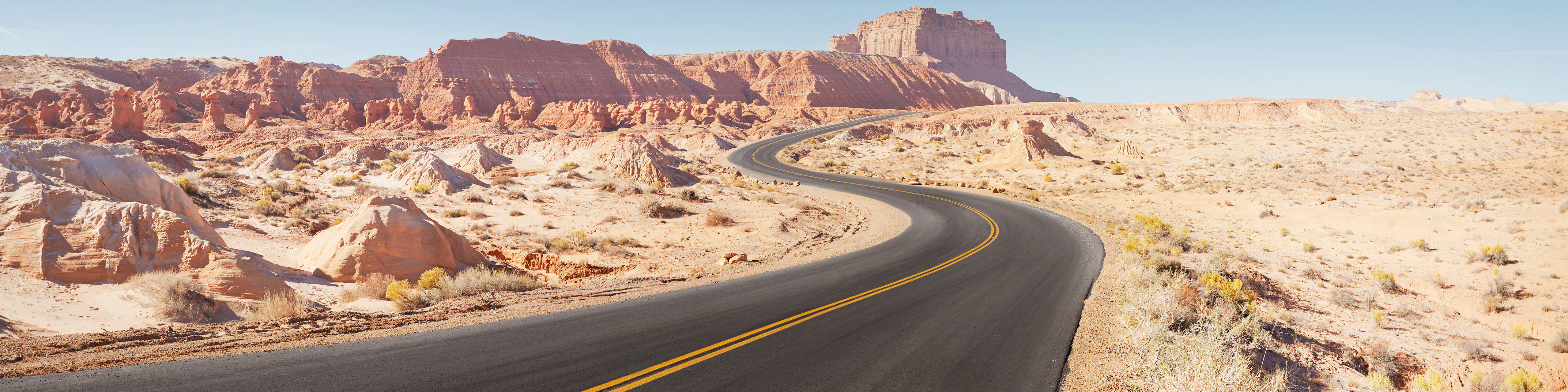 Winding empty road through arid desert landscape panoramic