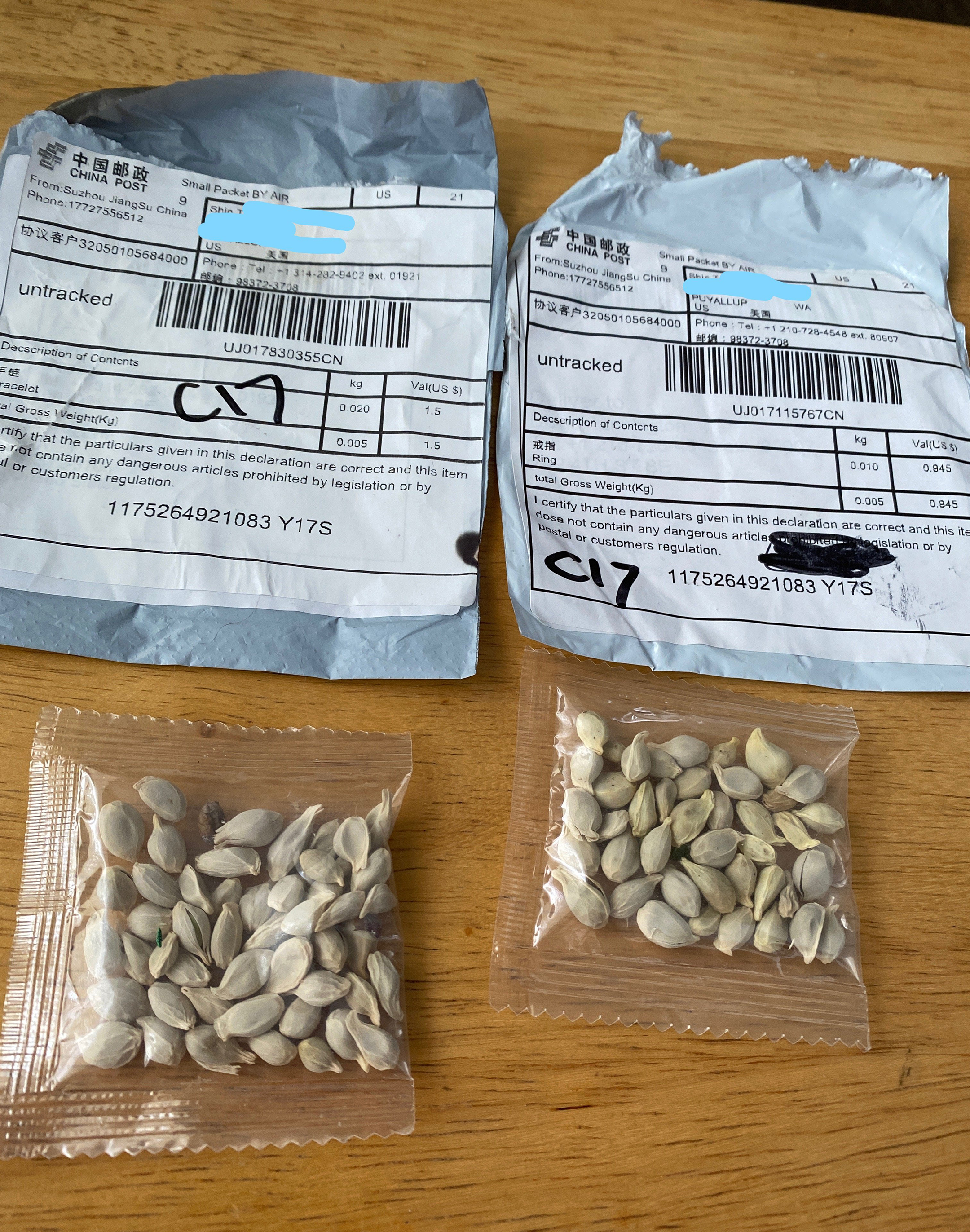 Two bags of seeds, sealed, above two open plastic mailing envelopes