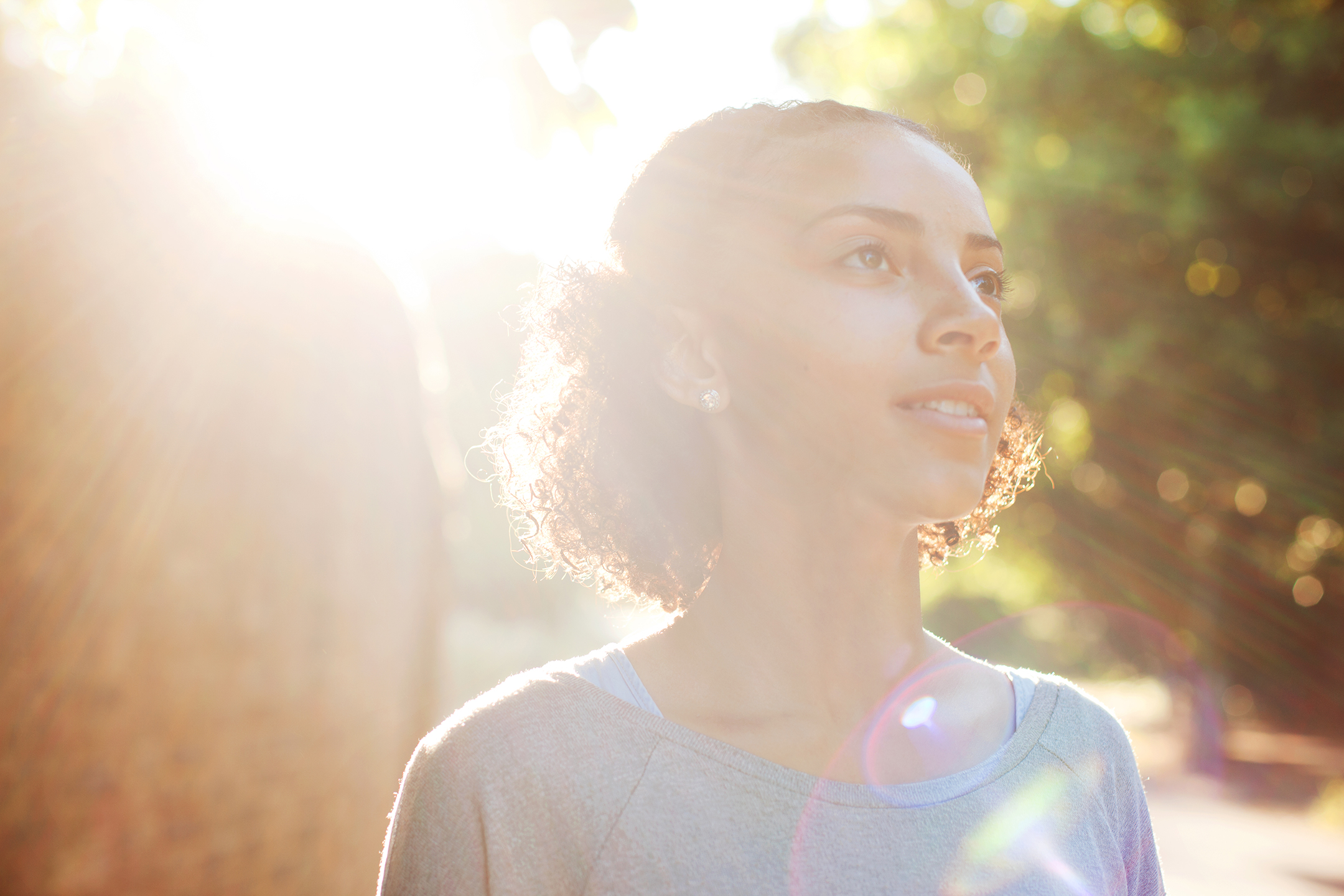 Young Black woman smiling as the sun forms a bright corona behind her