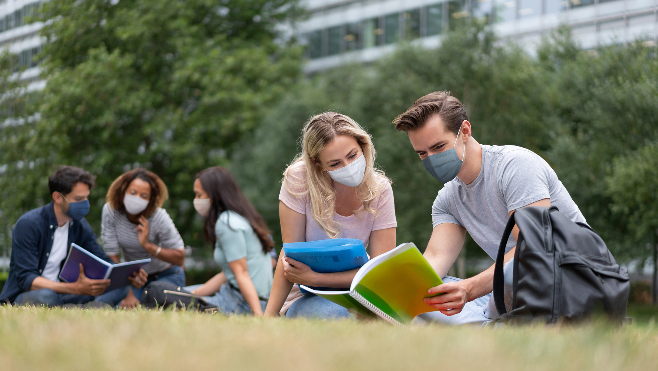 Students wearing a facemask while studying outdoors
