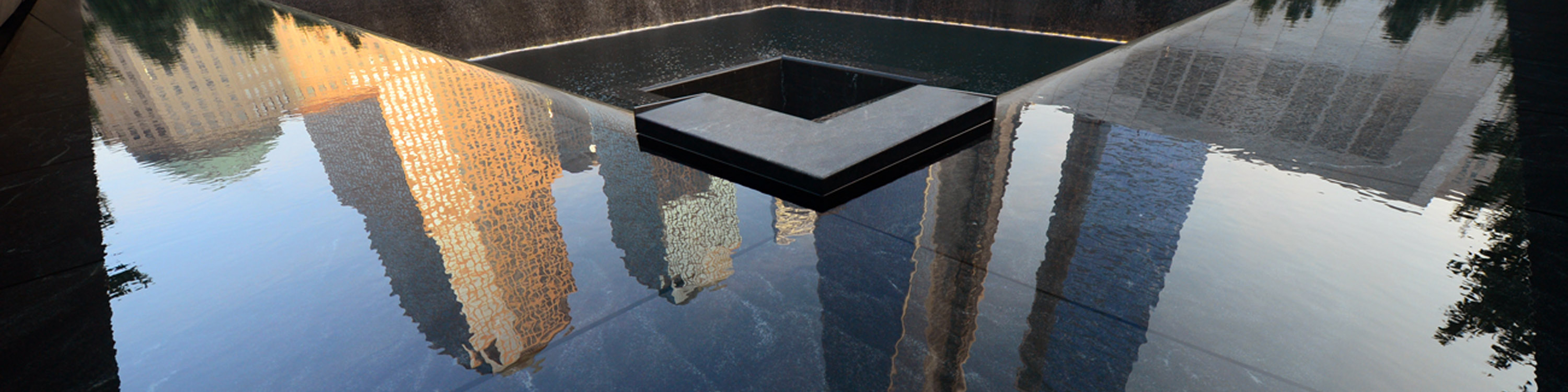 Building are reflected in one of the pools of the 9/11 Memorial during ceremonies for the twelfth anniversary of the terrorist attacks on lower Manhattan at the World Trade Center site on September 11, 2013 in New York City