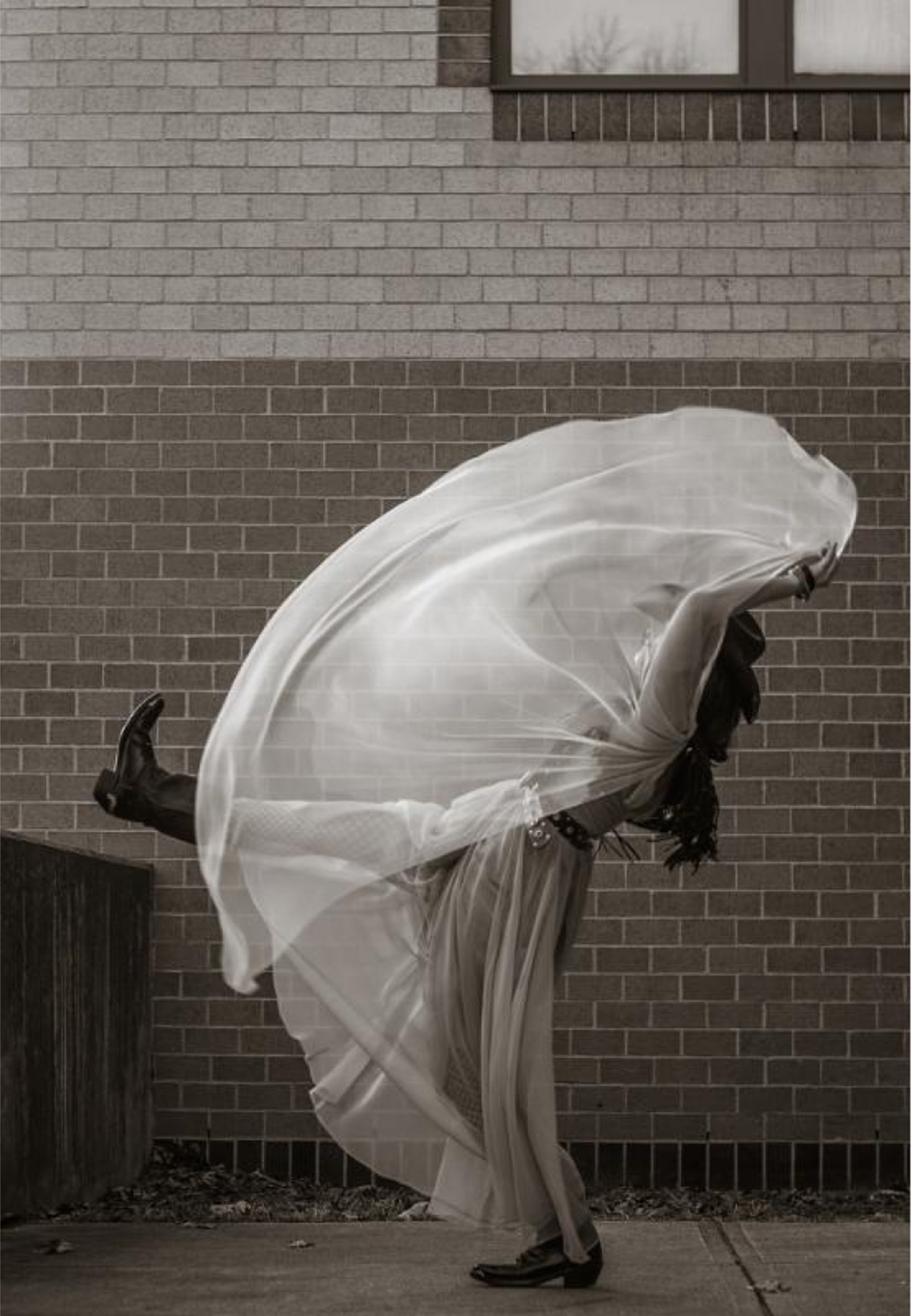 Photograph of a young black woman in a white dress kicking as part of a dance routine