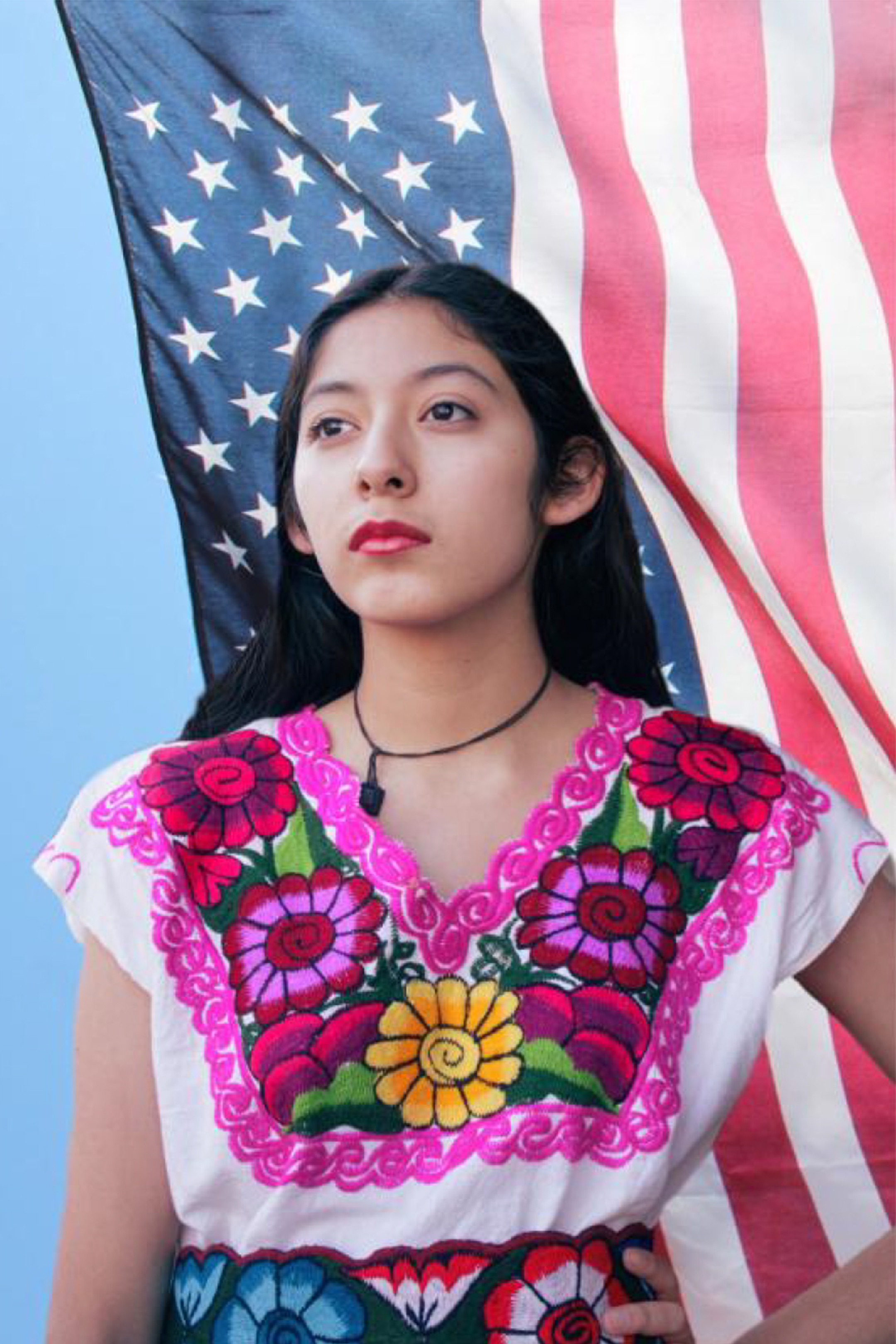 Young woman in traditional Mexican clothing standing in front of a flowing American flag
