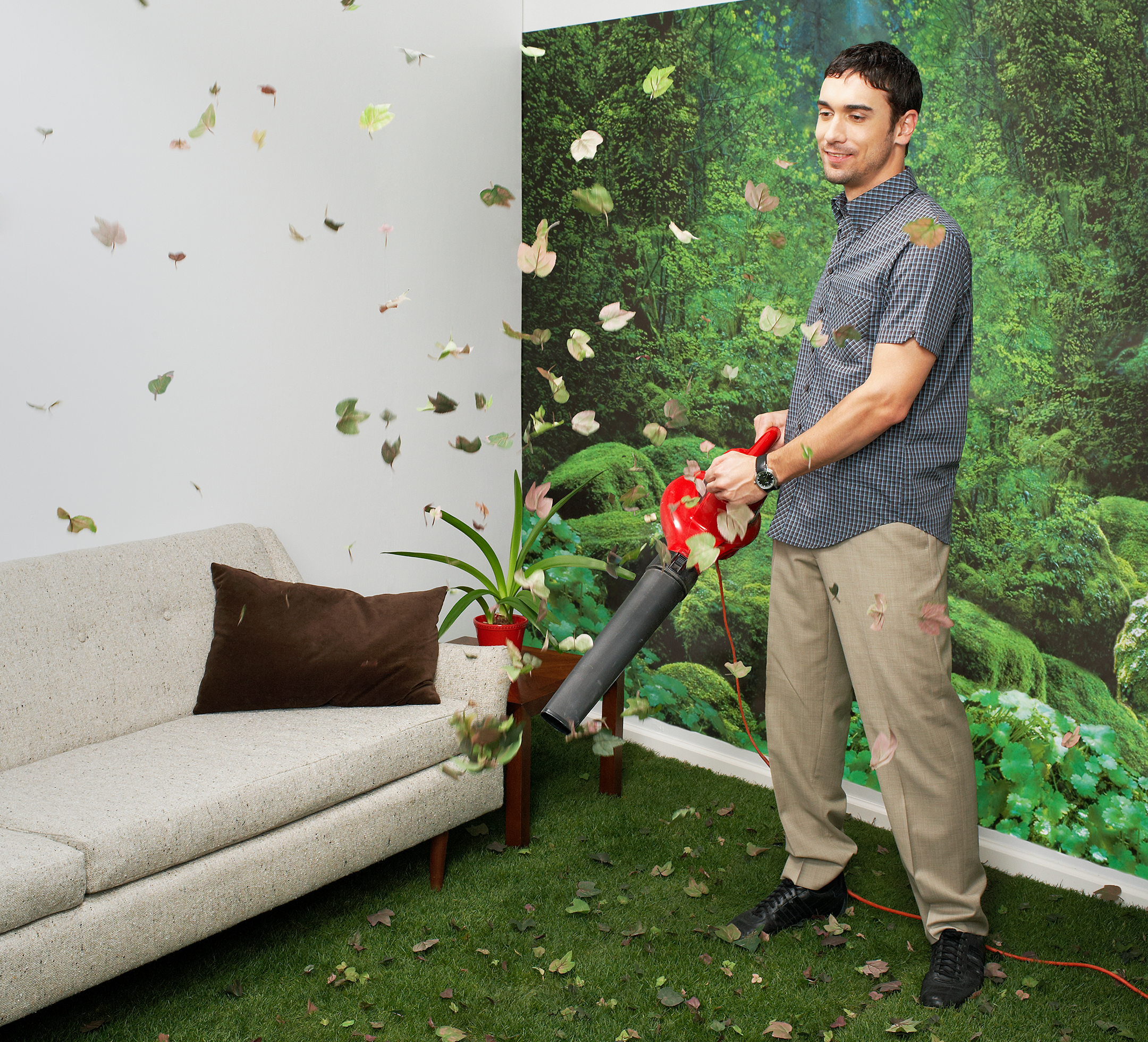 Young man blowing leaves in living room decorated with nature