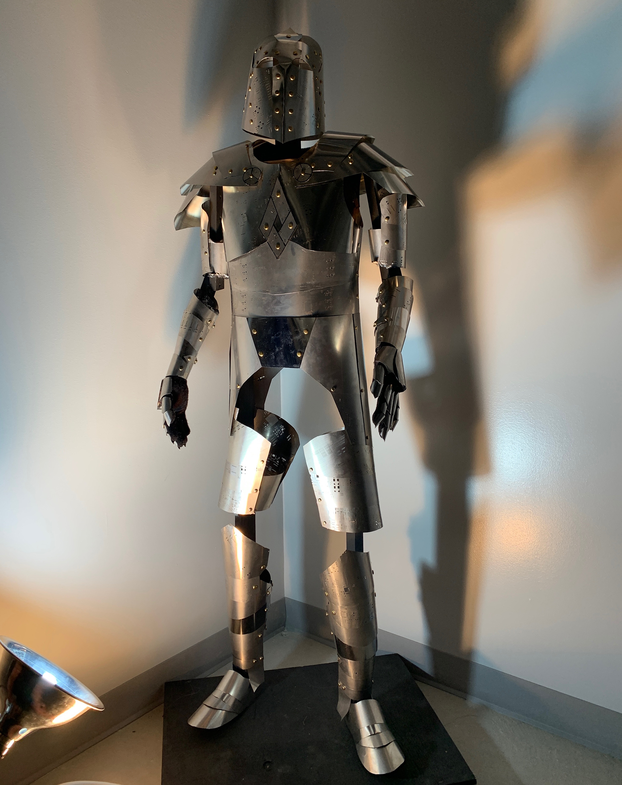 A suit of silver armor lit from below against a white wall