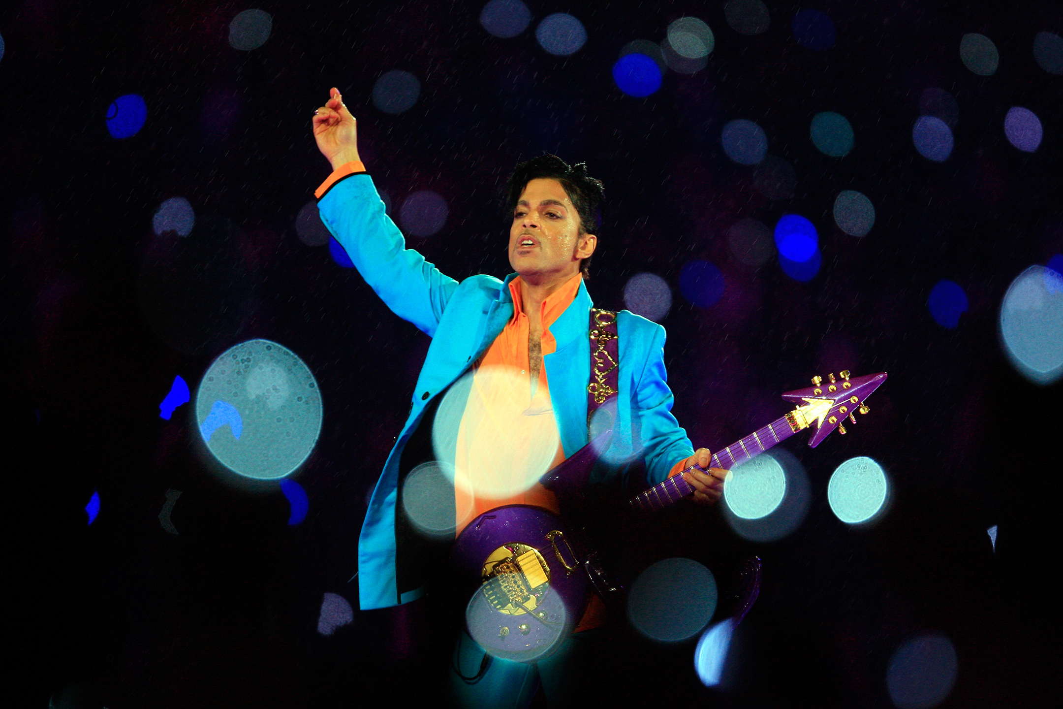 Prince raising his arms during a performance in the rain